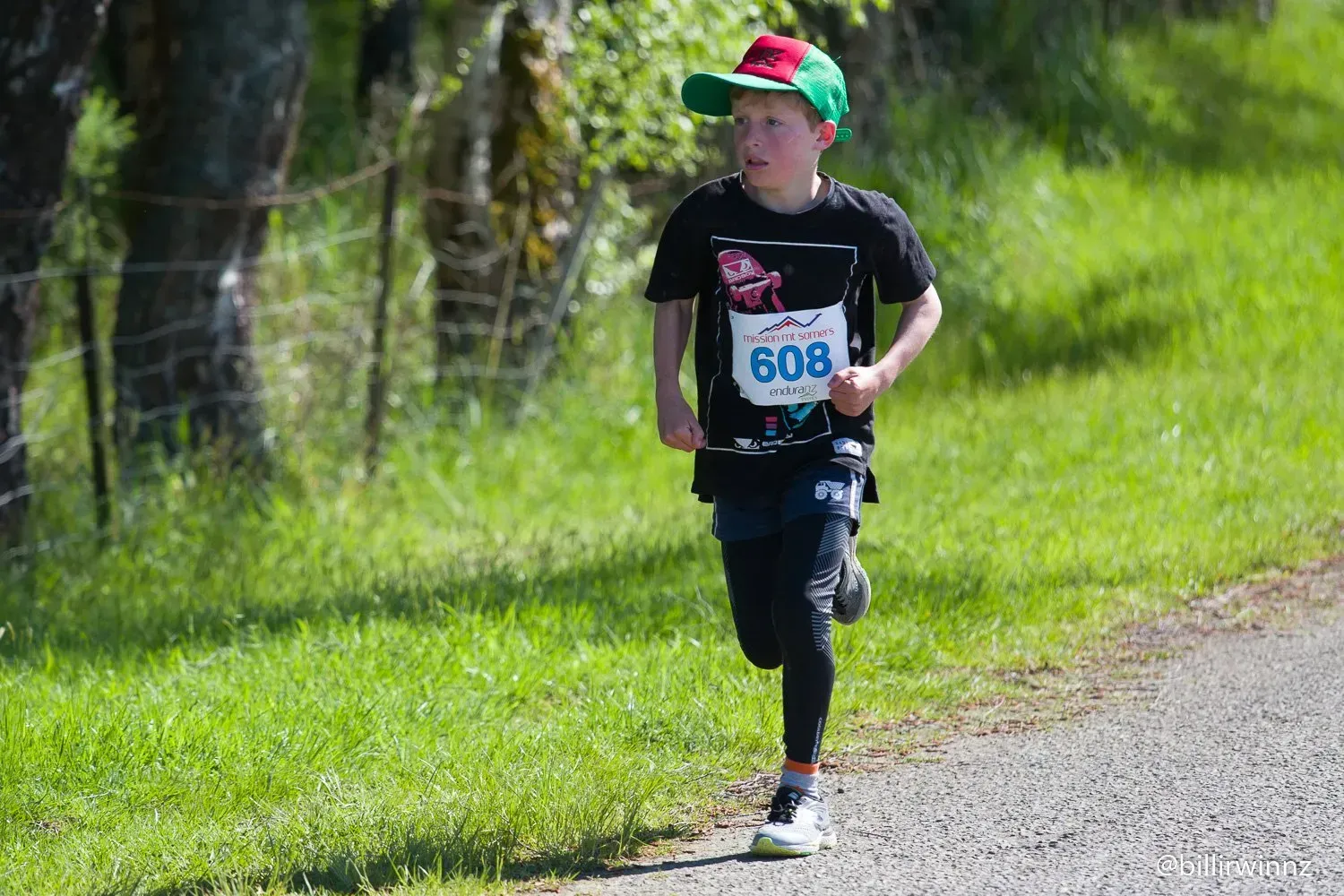 A young boy is running a race on a dirt road.