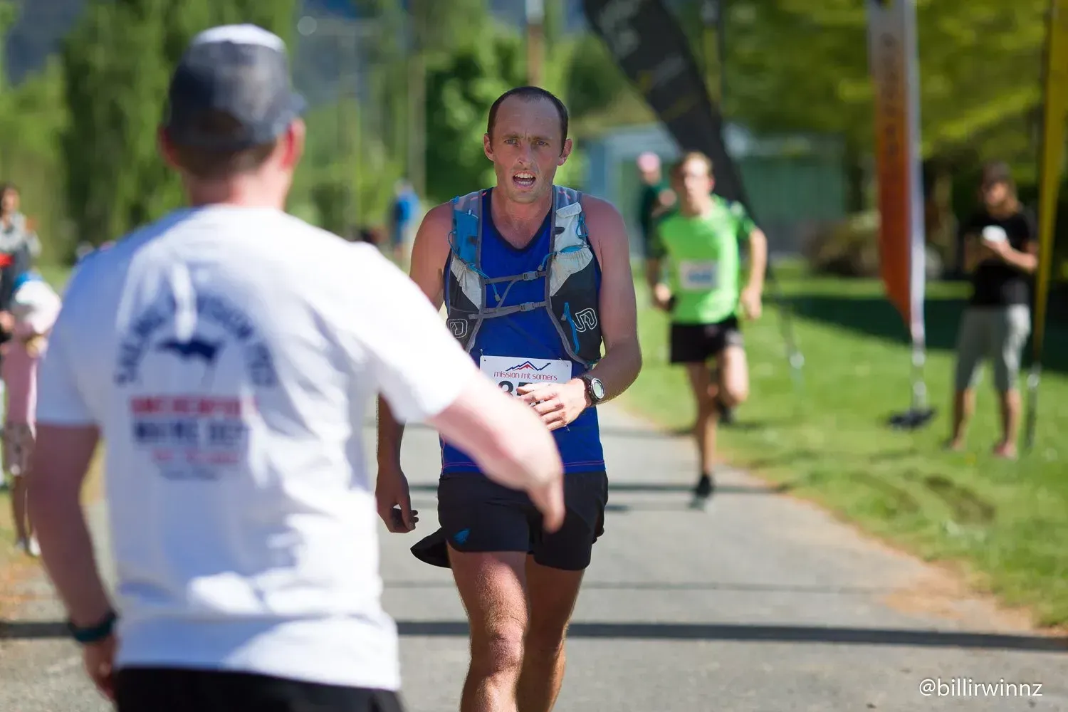 A man in a white shirt is giving a handshake to a runner in a race.