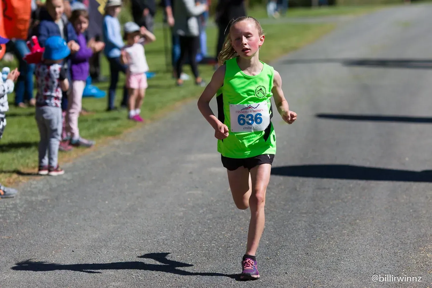 A young girl is running a race on a road.