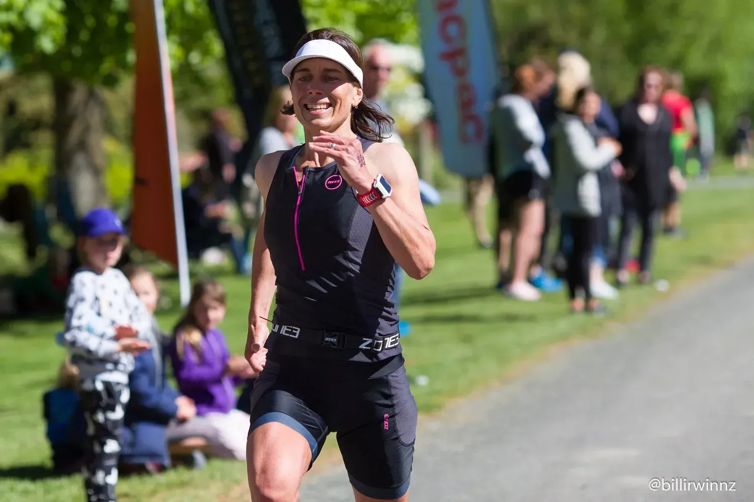 A woman is running in a triathlon in front of a crowd of people.