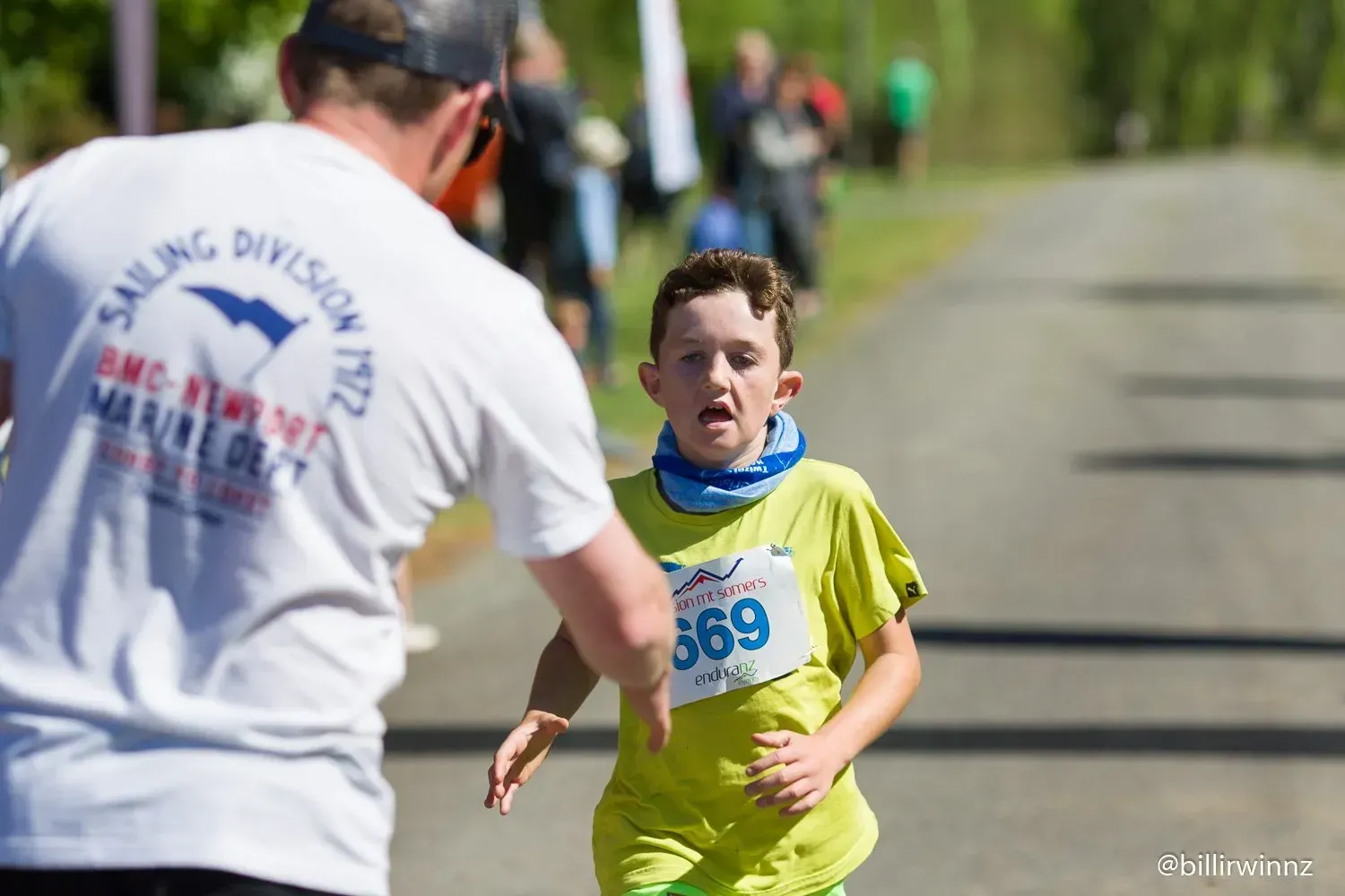 A man in a white shirt is helping a young boy run a race.