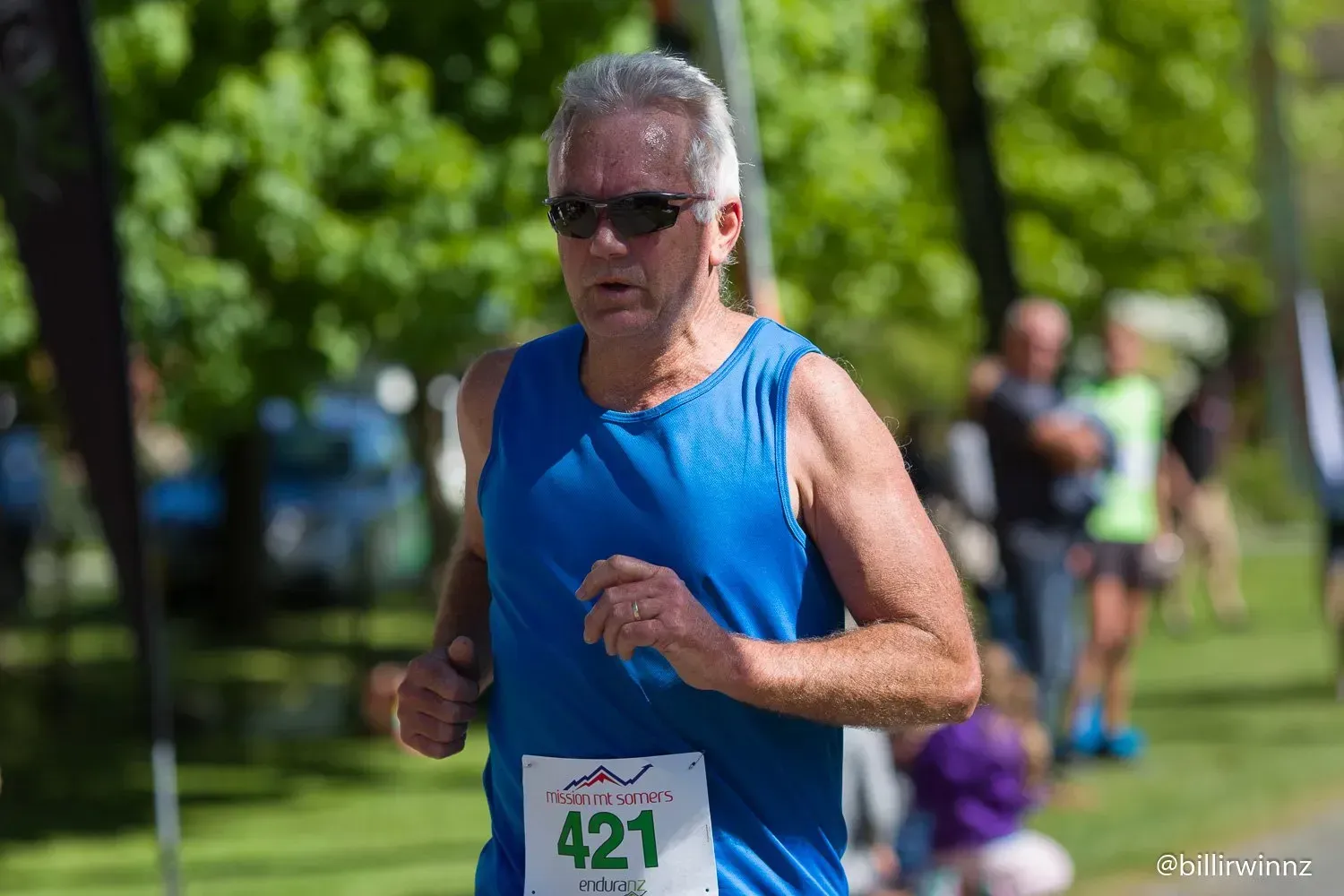 A man in a blue tank top is running in a race.