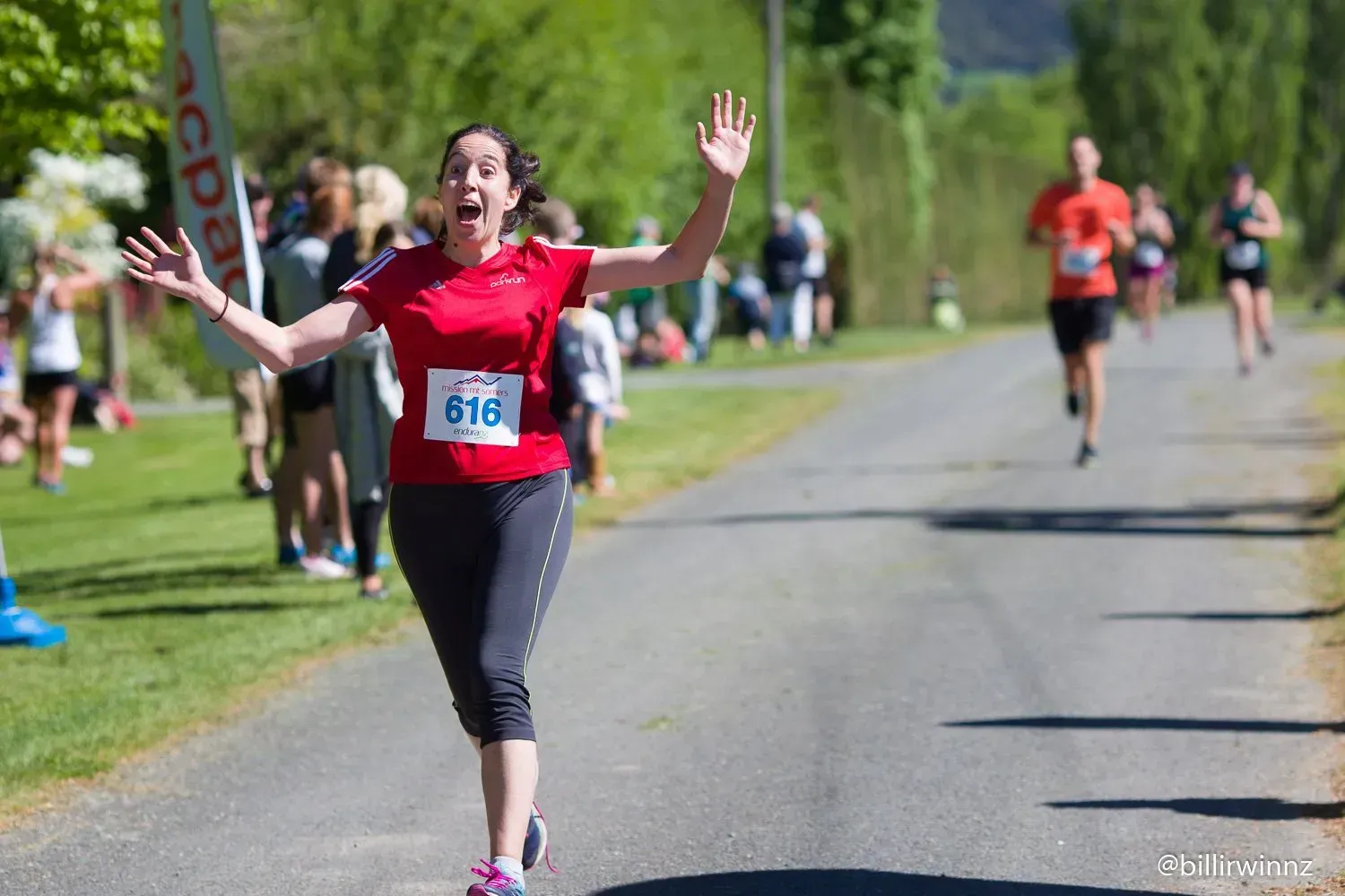 A woman in a red shirt is running in a race.