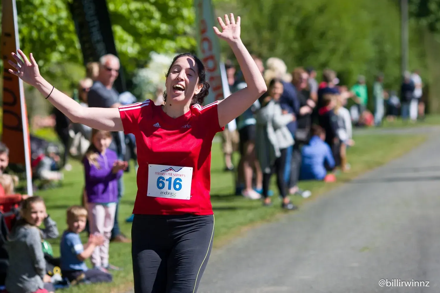 A woman is running in a race with her arms in the air.