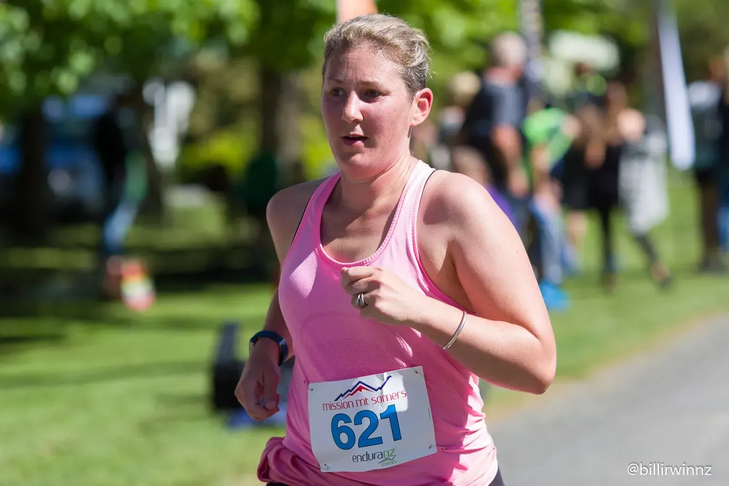 A woman in a pink tank top is running in a race.