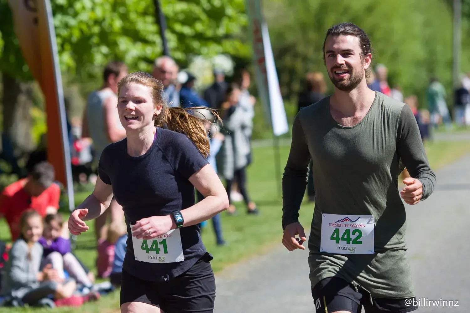 A man and a woman are running in a race in a park.