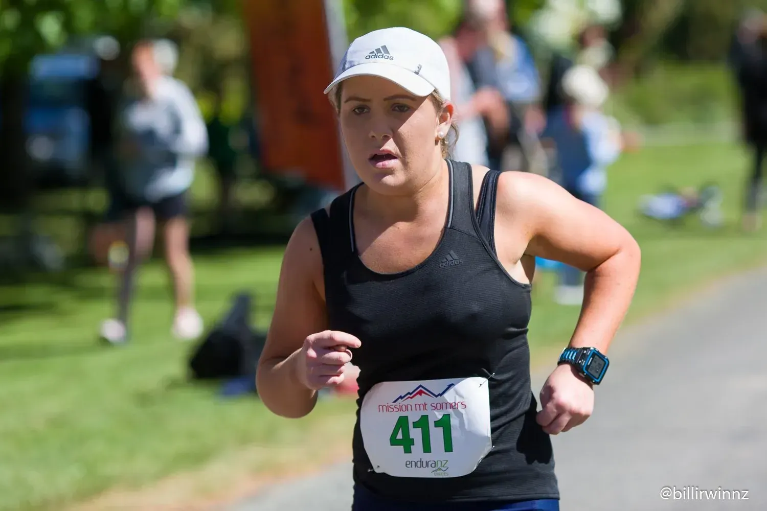A woman is running in a race with the number 411 on her shirt.