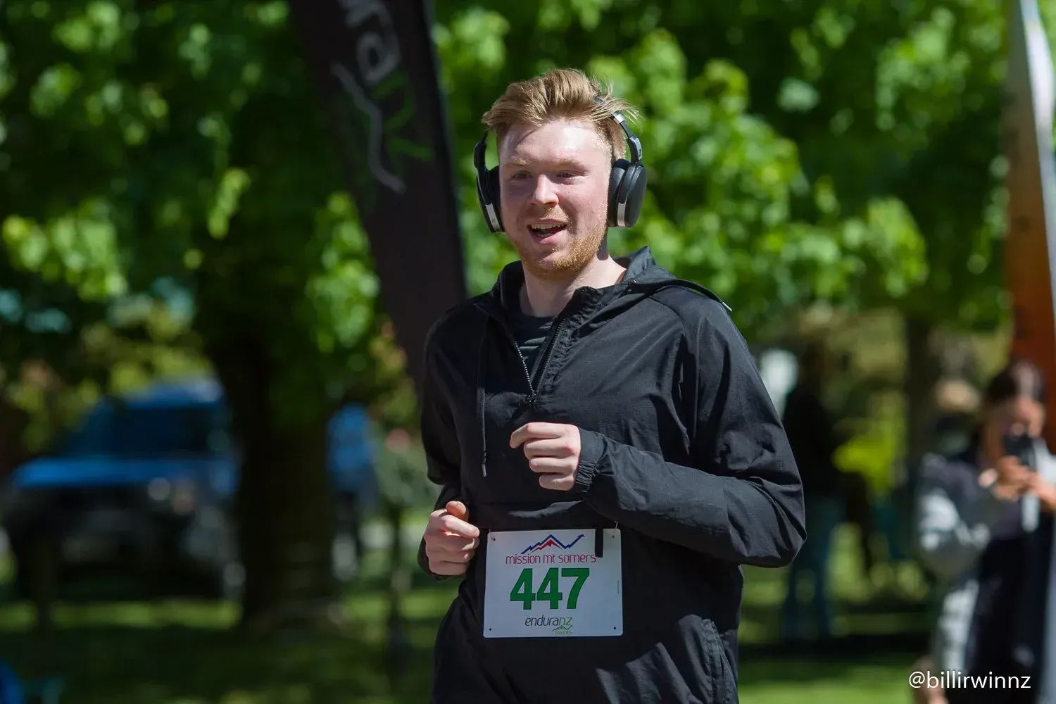 A man wearing headphones is running in a park.