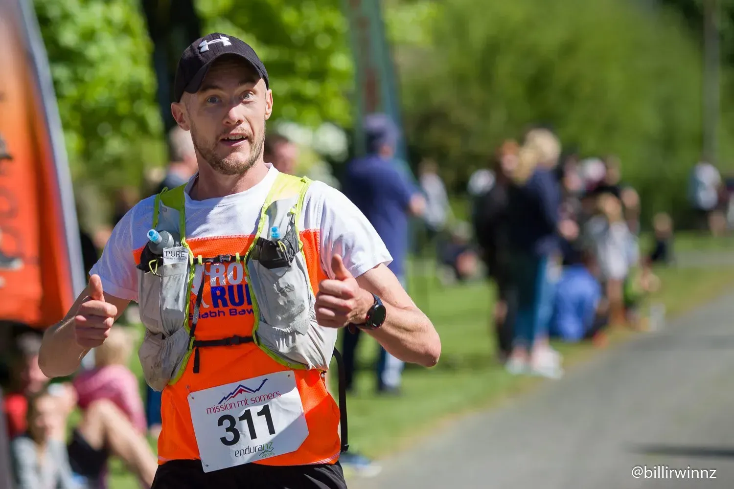 A man is running a race and giving a thumbs up.