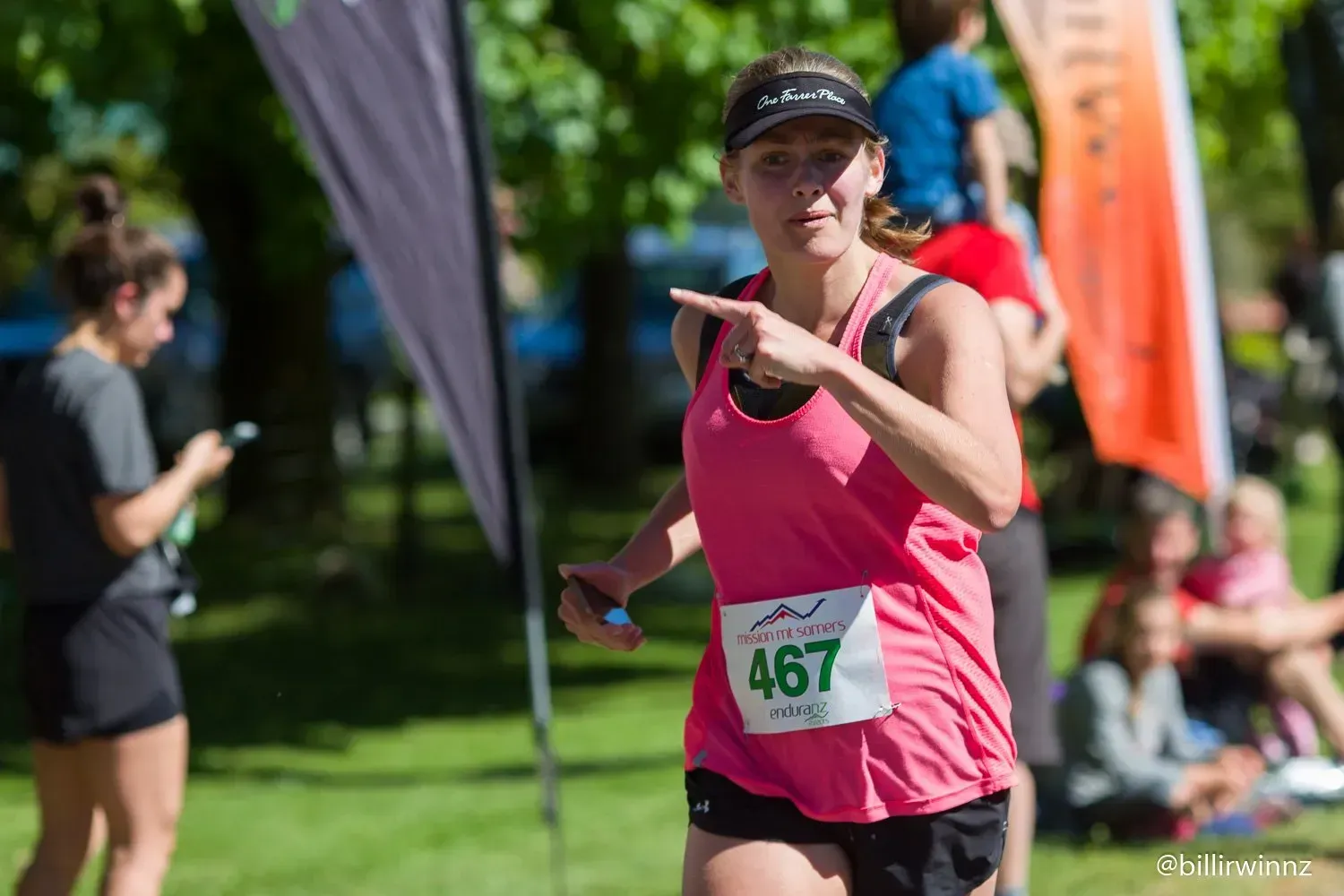 A woman is running in a race and pointing at the camera.