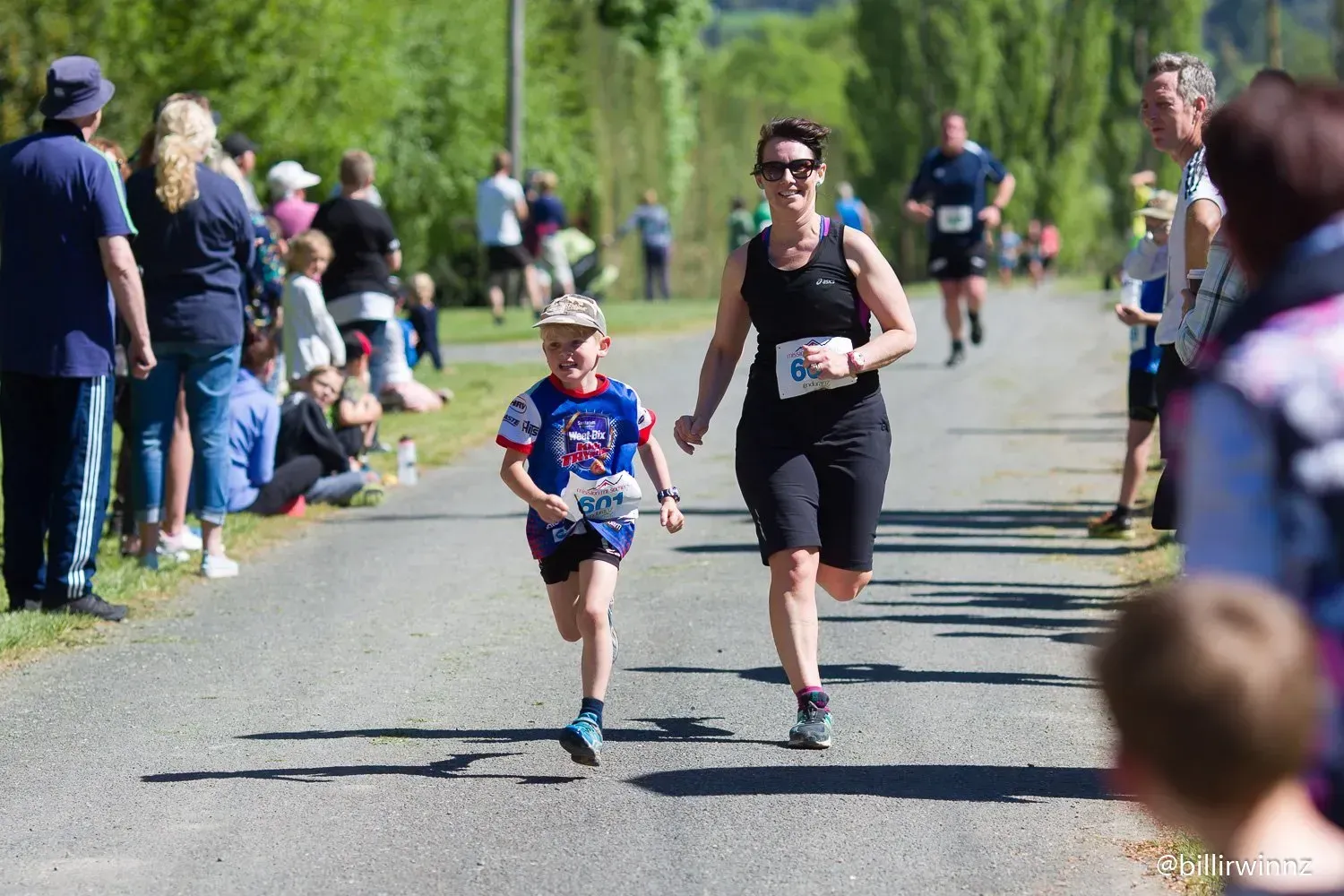 A woman and a boy are running down a road.