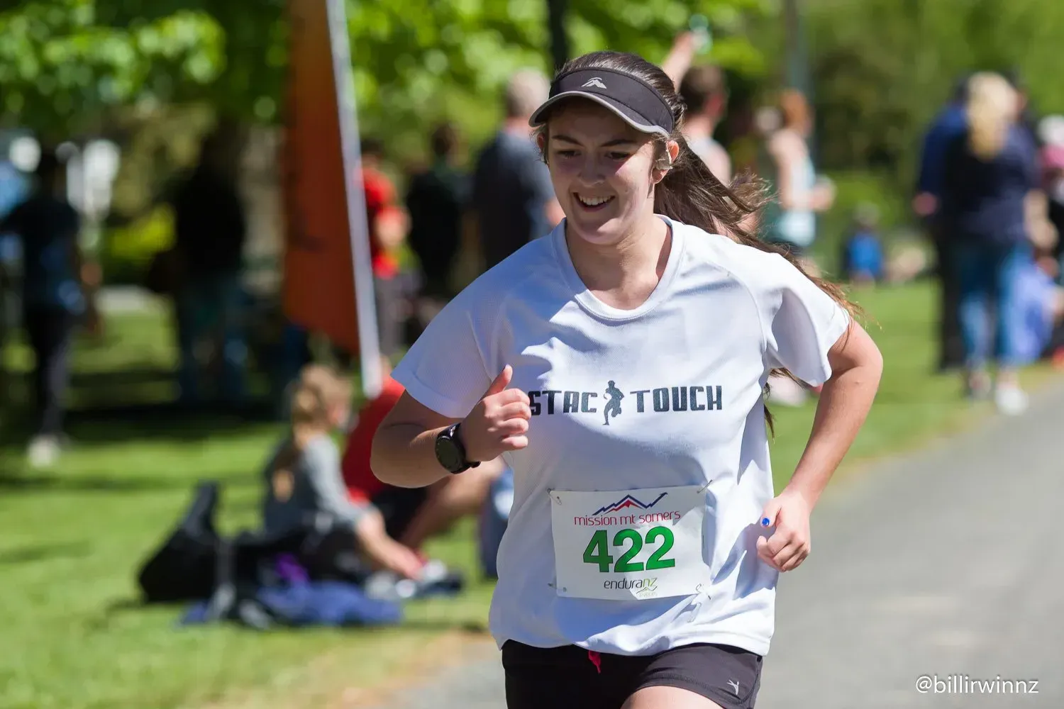 A woman is running in a race and giving a thumbs up.