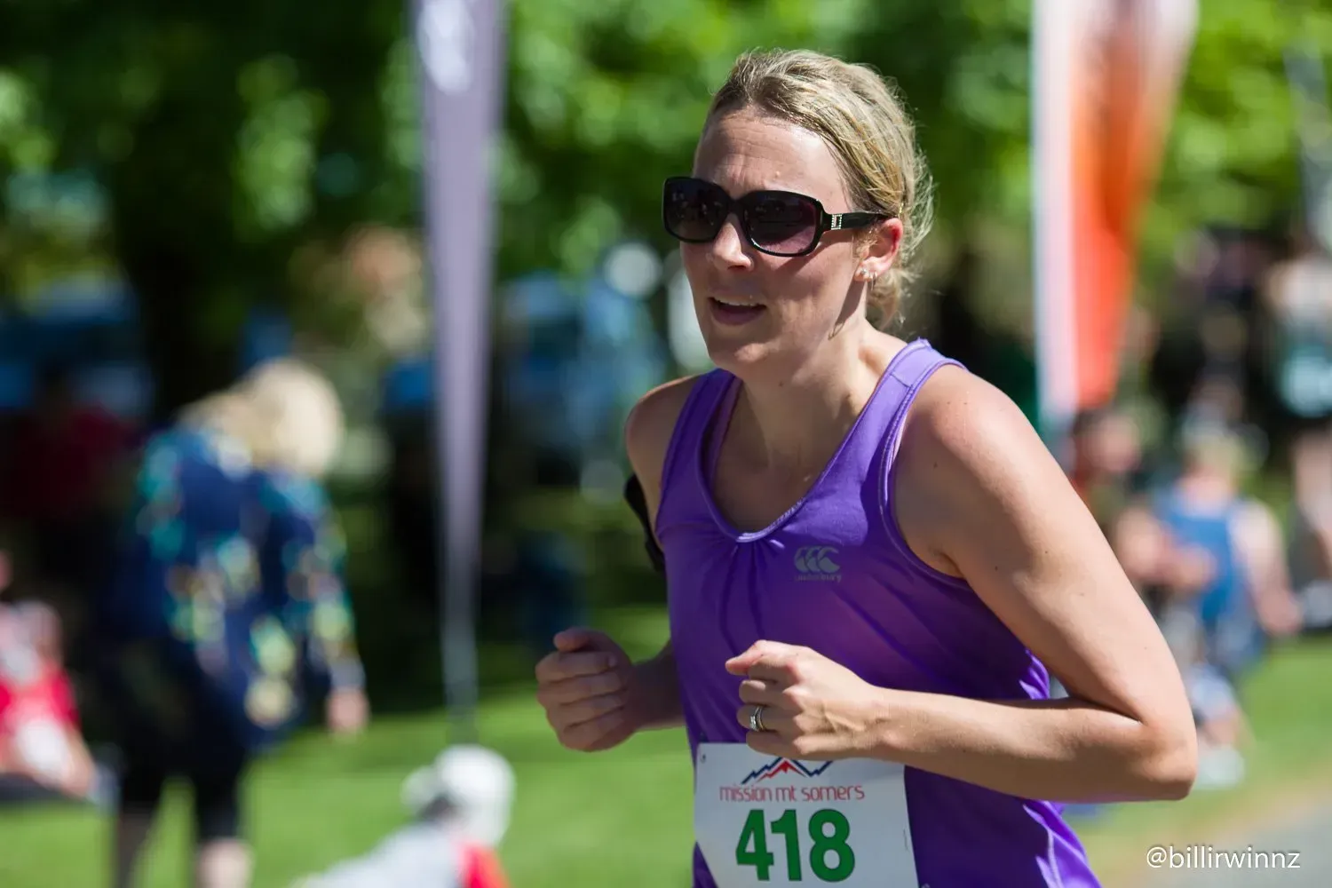 A woman in a purple tank top is running in a race.