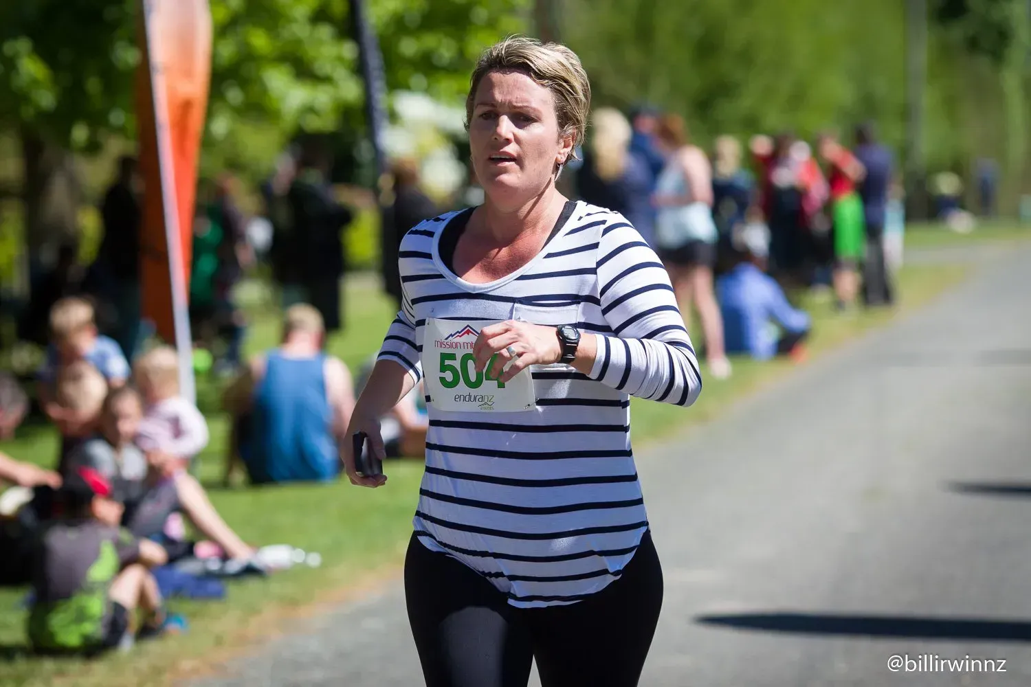 A woman is running in a race with a number 50 on her shirt.