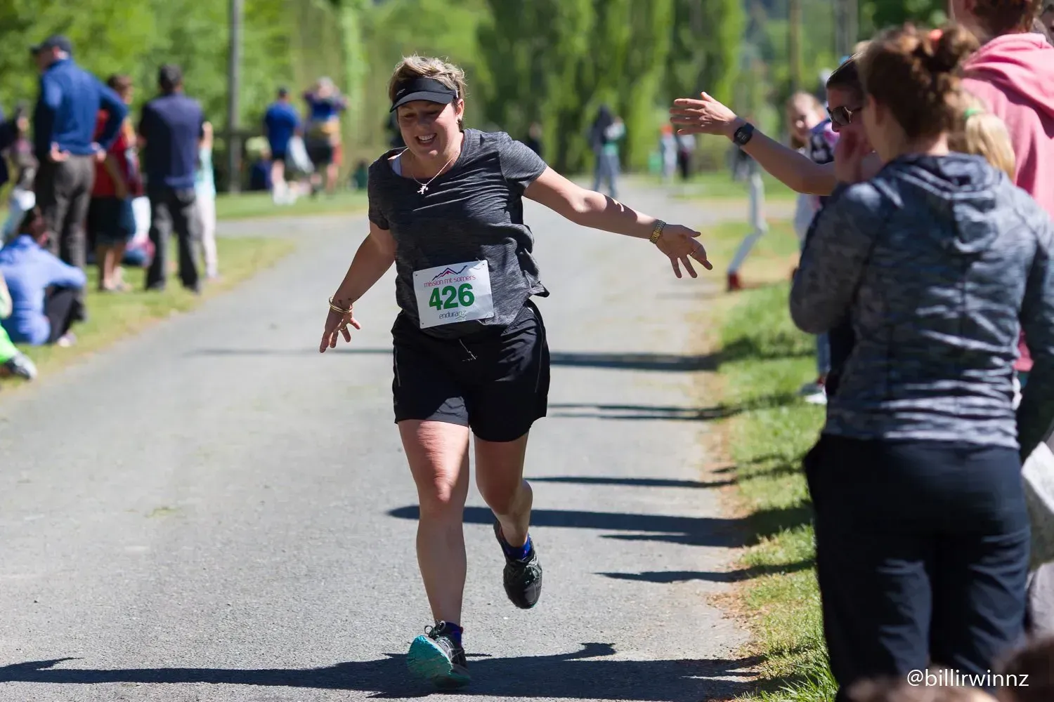 A woman is running down a road while a crowd watches.