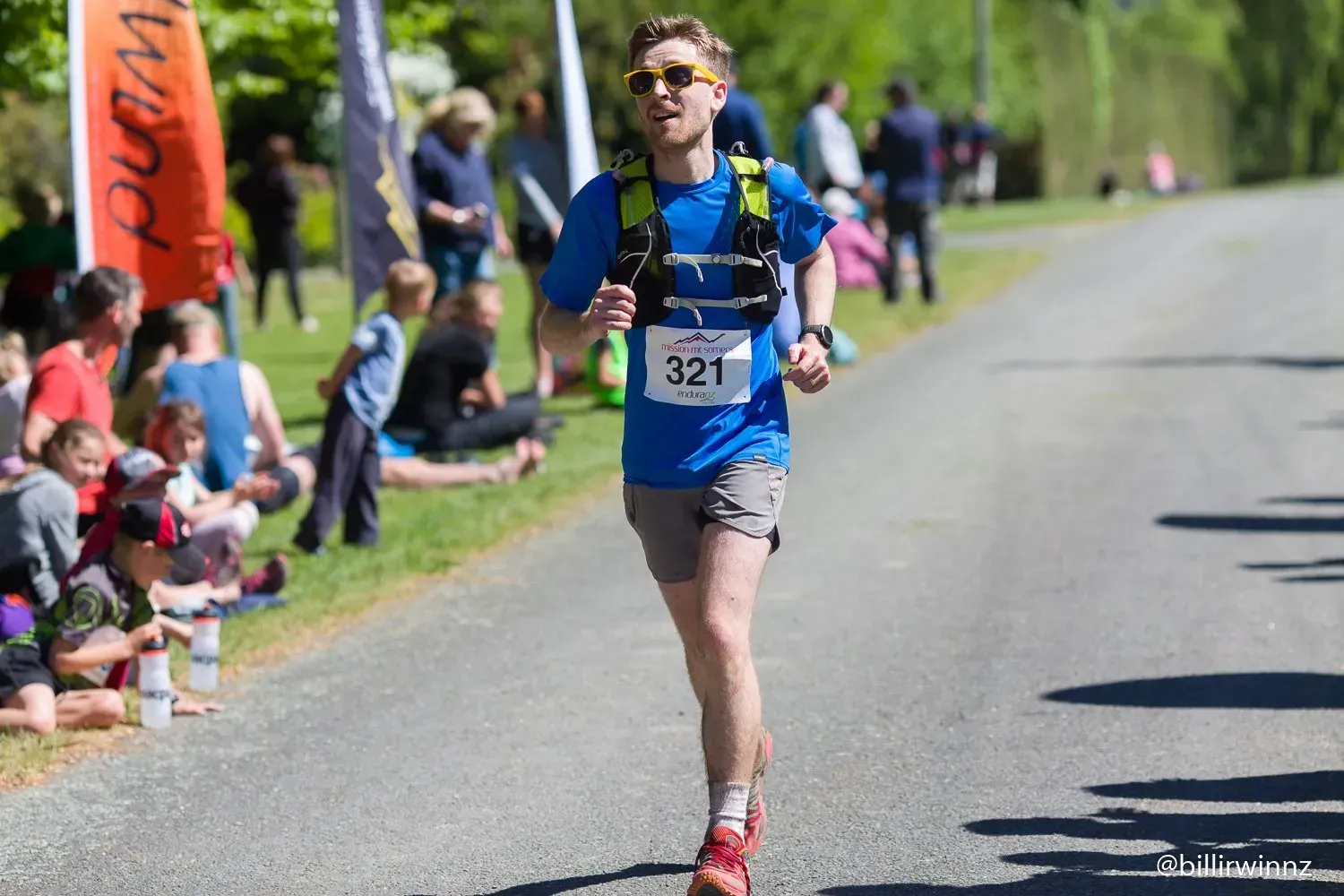 A man is running down a road with a number on his shirt.
