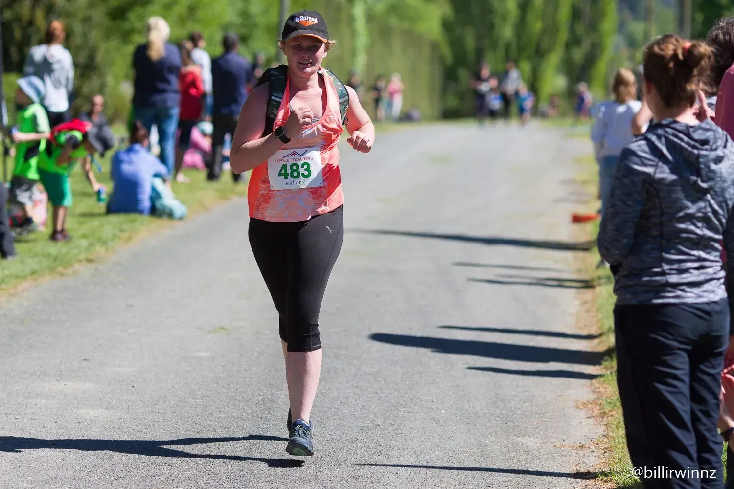 A woman is running in a race with the number 483 on her shirt.