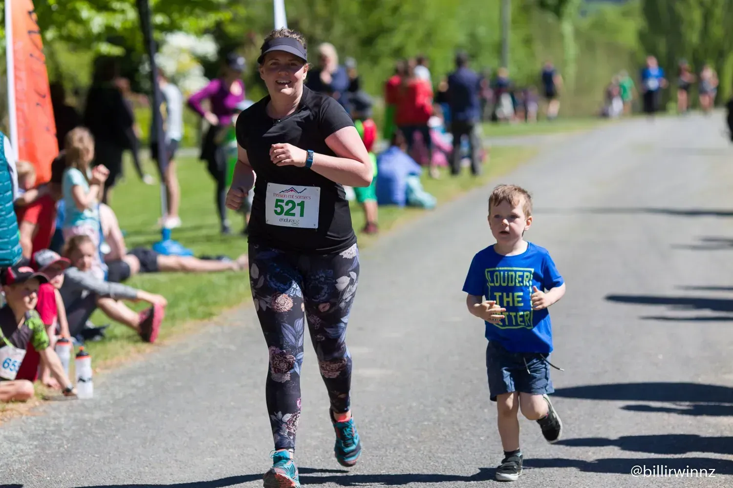 A woman and a child are running down a road.