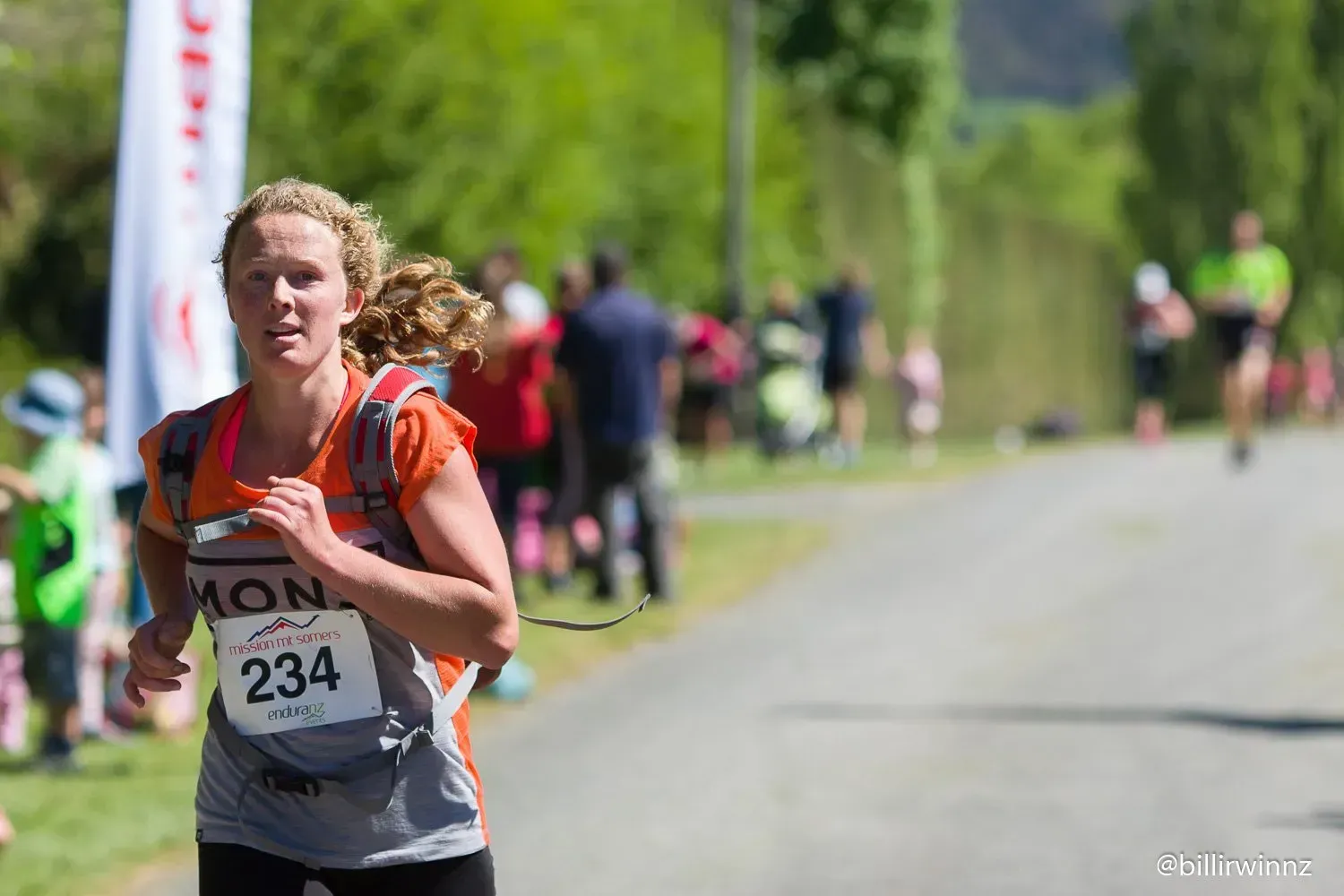 A woman is running in a race with the number 234 on her shirt.