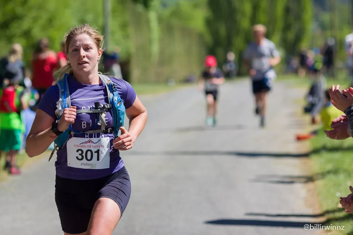 A woman is running in a race with a number 301 on her shirt.