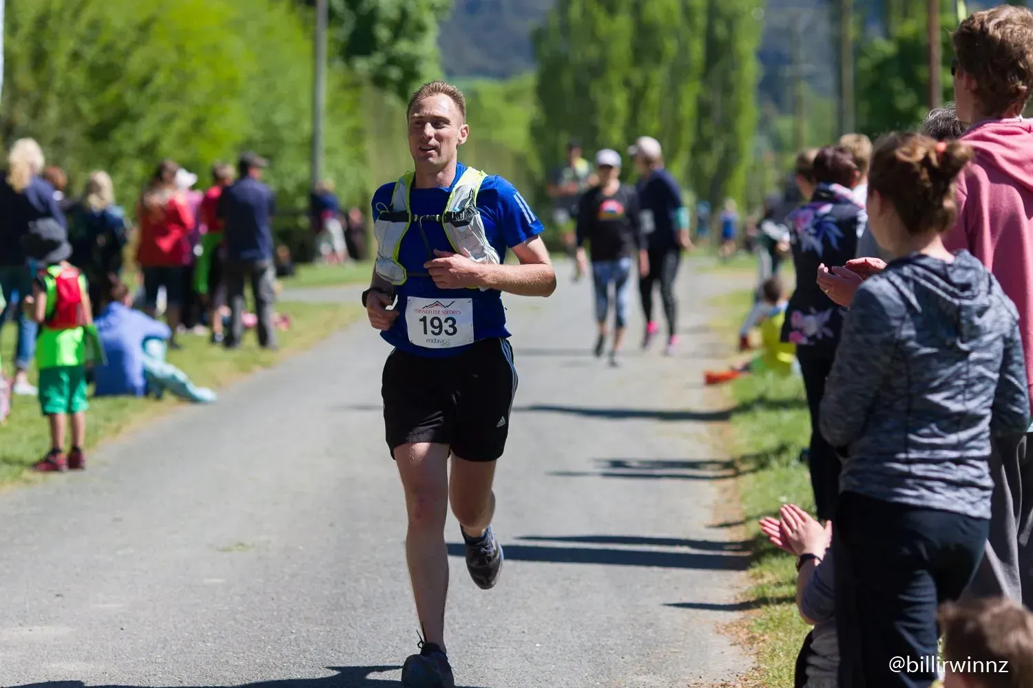 A man is running down a road with the number 193 on his shirt.
