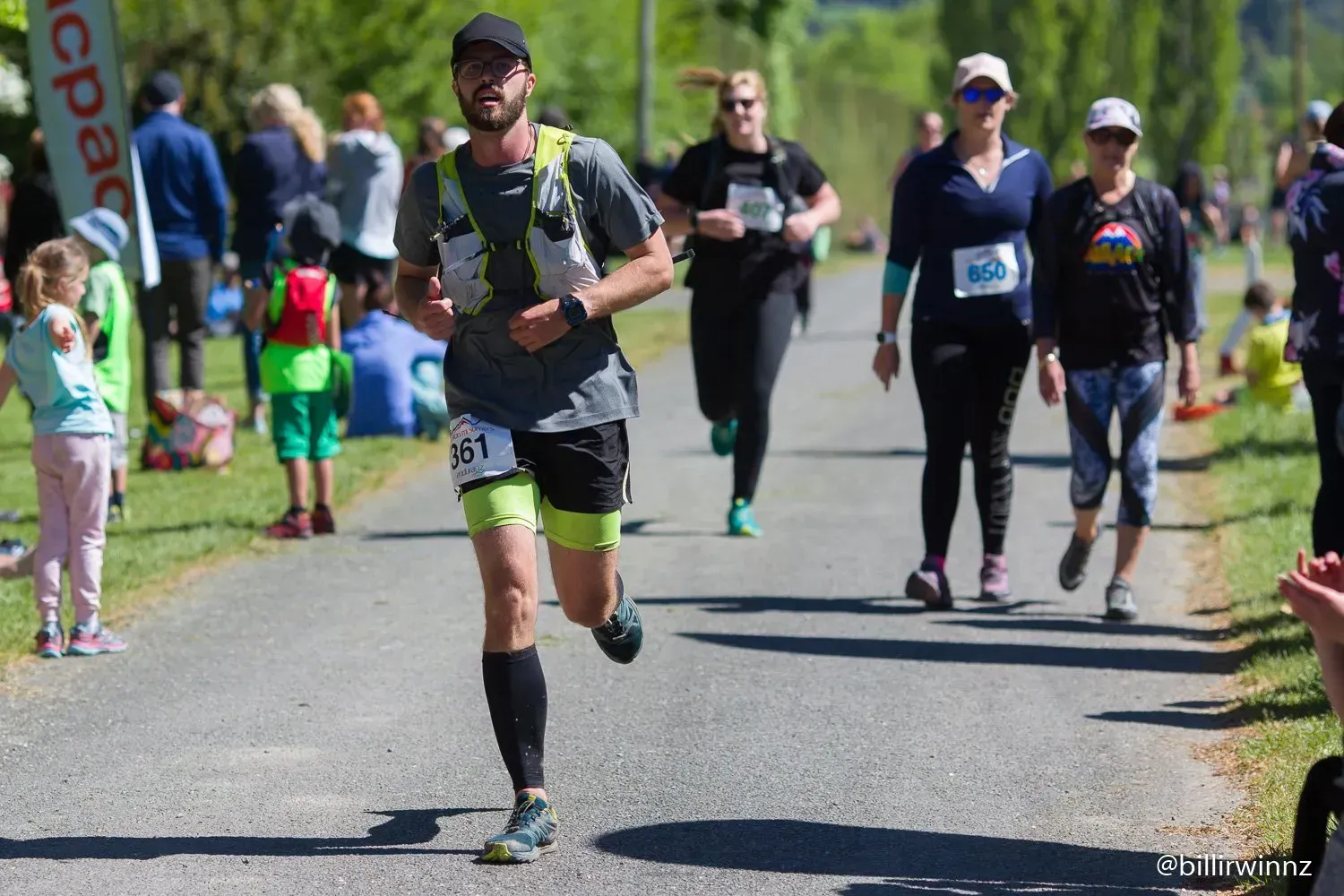 A man is running in a race with a group of people walking behind him.
