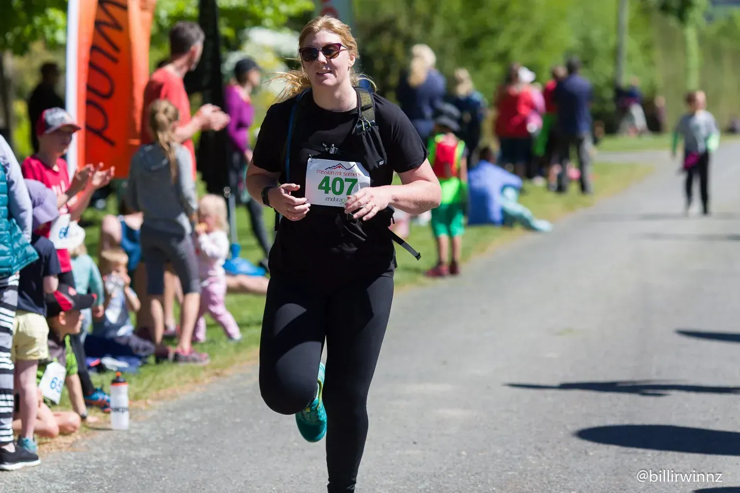 A woman is running in a race with the number 407 on her shirt.