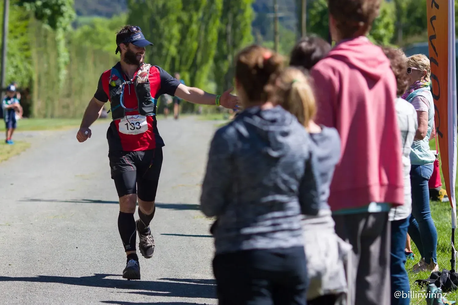 A man is running down a road and giving a woman a high five.