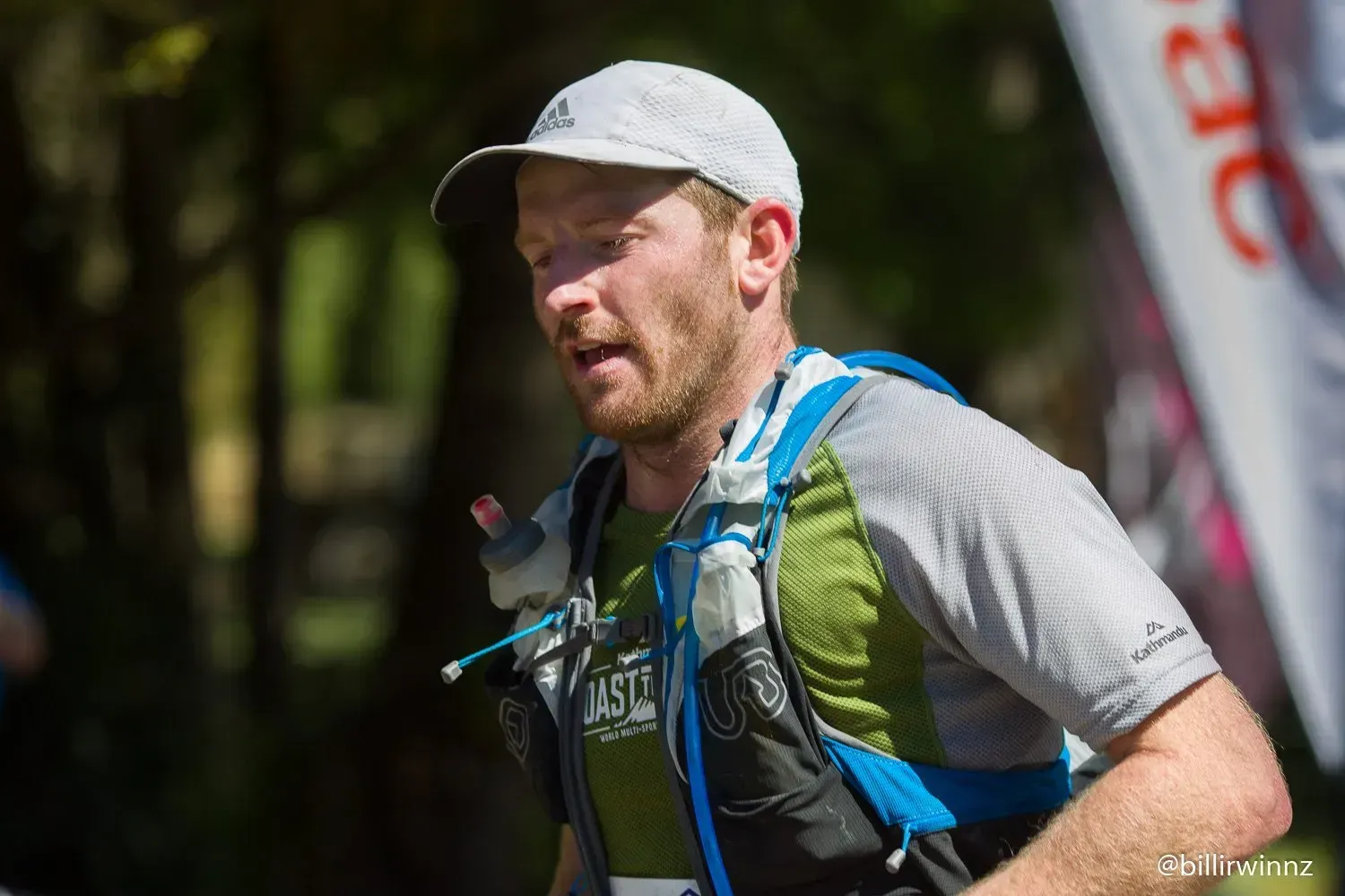 A man wearing a hat and a backpack is running in a race.