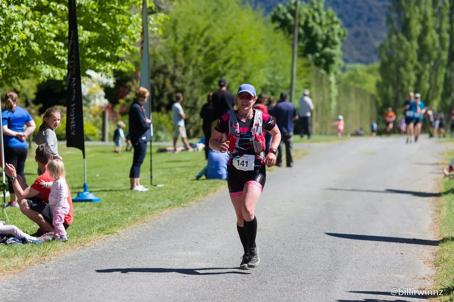 A woman is running down a road in a park.