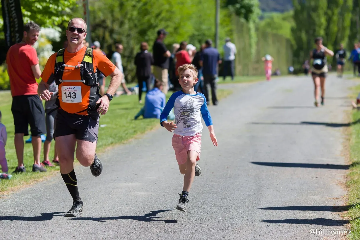 A man and a little girl are running down a road.