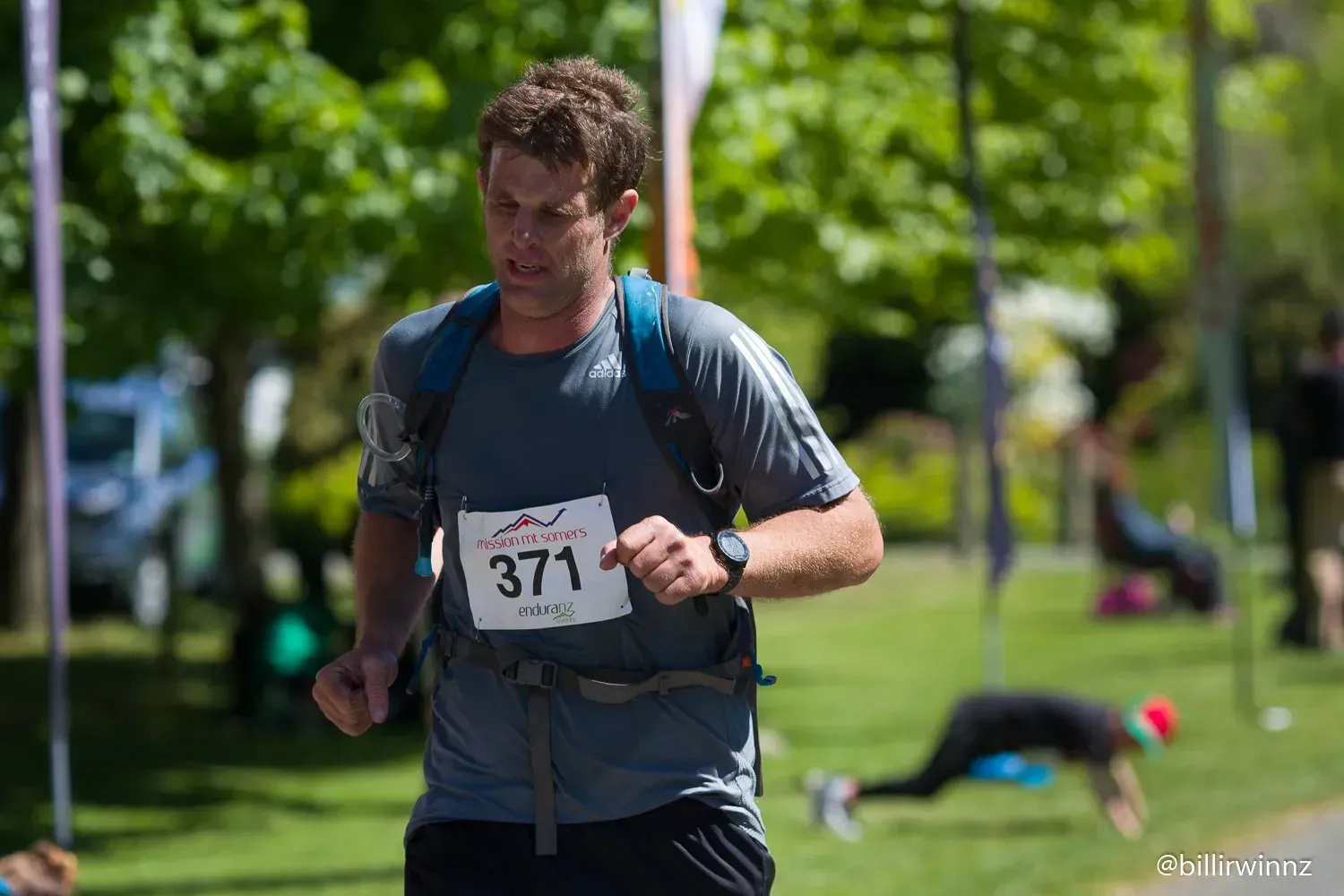 A man with a backpack is running in a park.