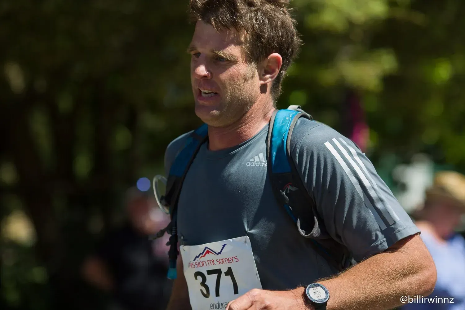 A man is running in a race with the number 371 on his shirt.