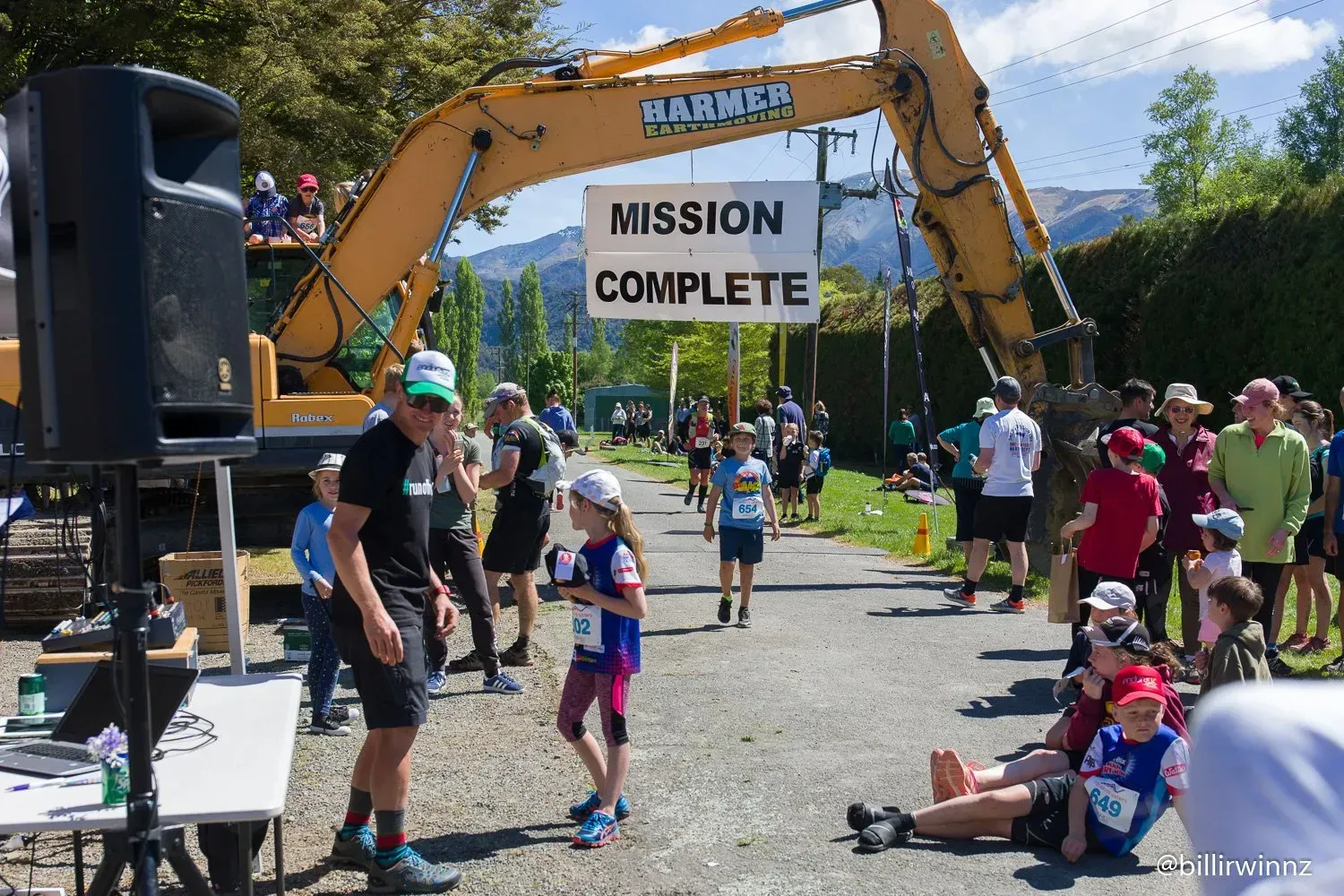 A group of people are gathered around a sign that says mission complete.