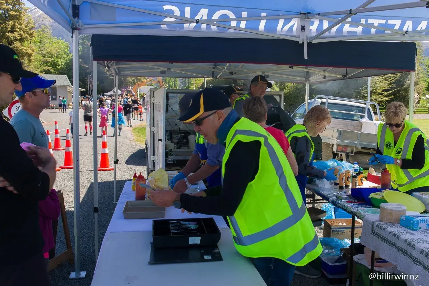 A group of people are standing around a table under a tent.