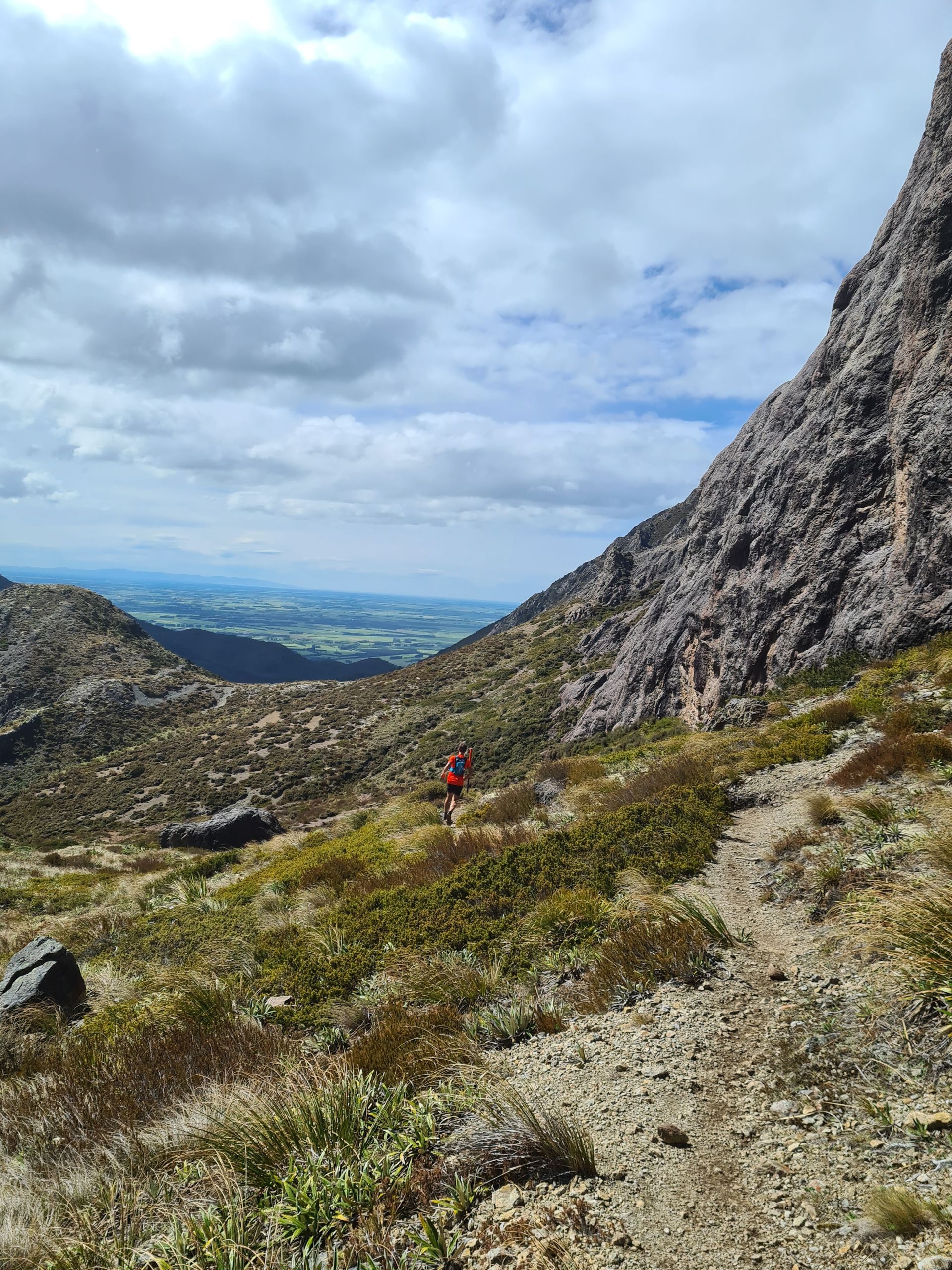A person is walking down a dirt path in the mountains.