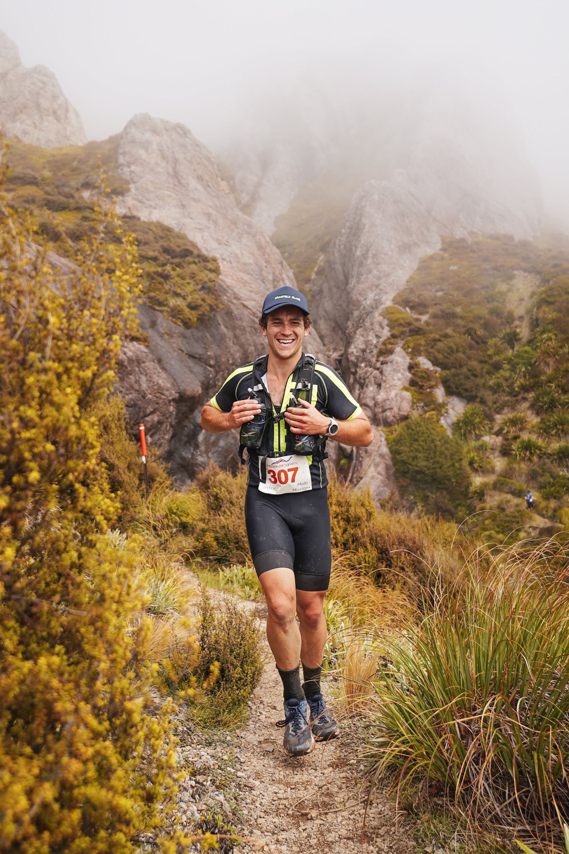 A man is running on a trail in the mountains.