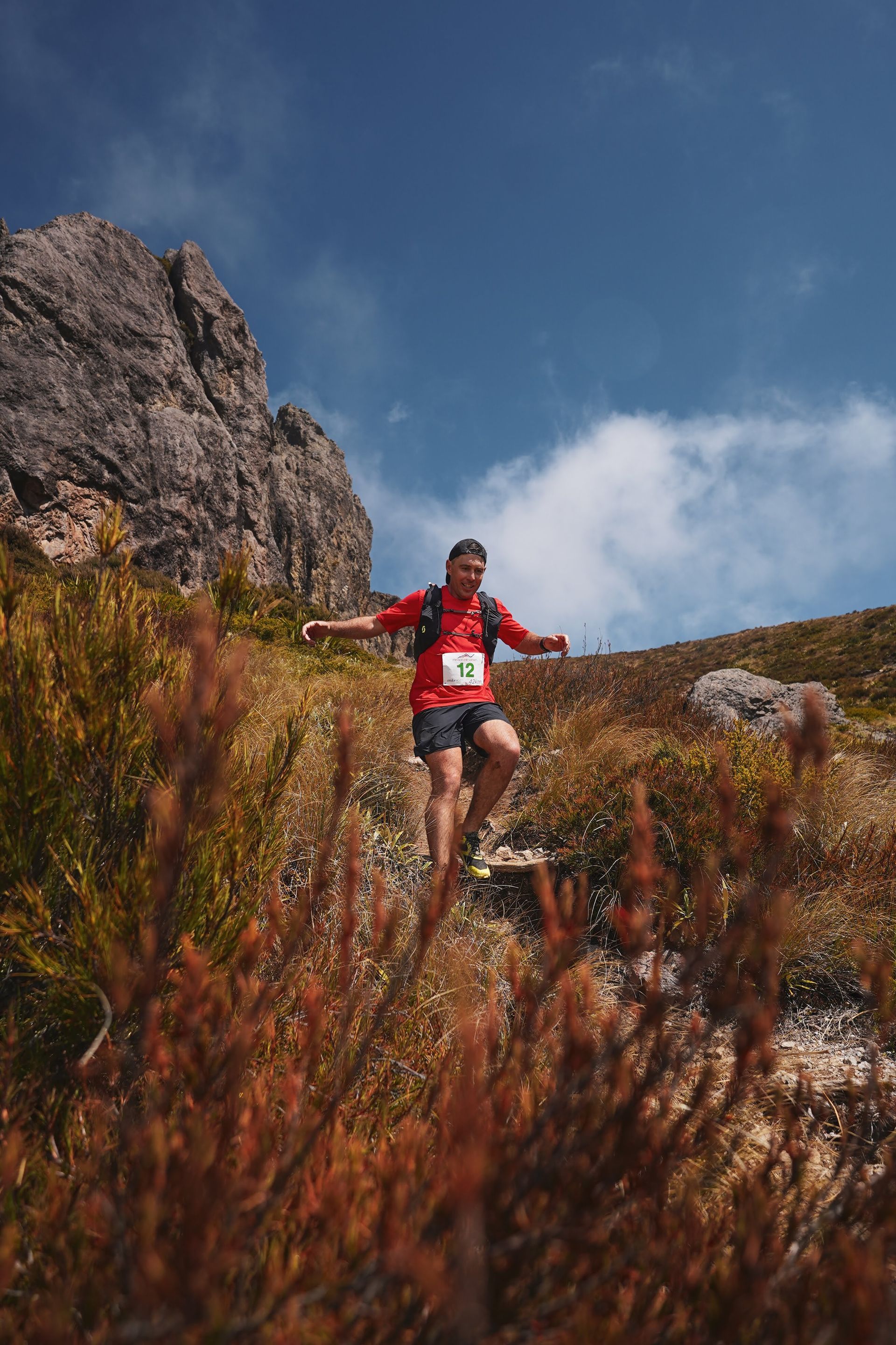 A man is running on a trail in the mountains.