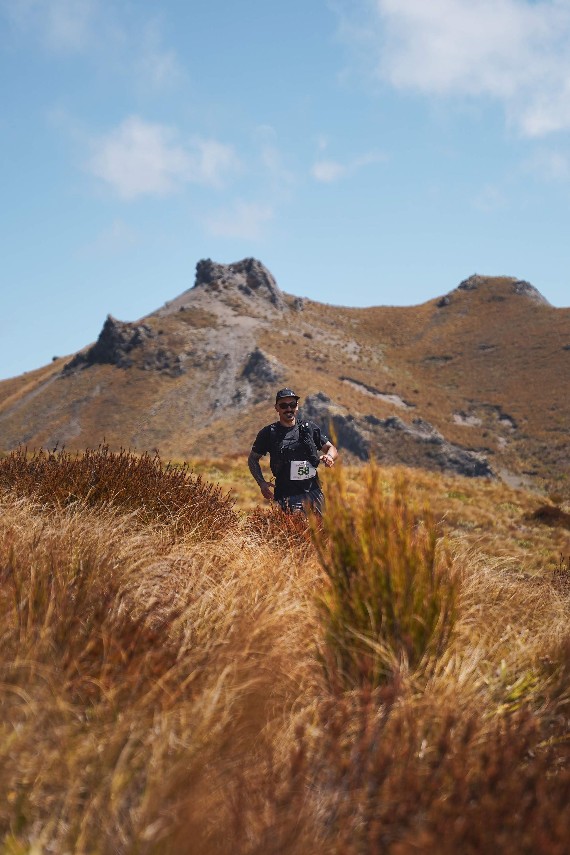 A man is running in a field with a mountain in the background.