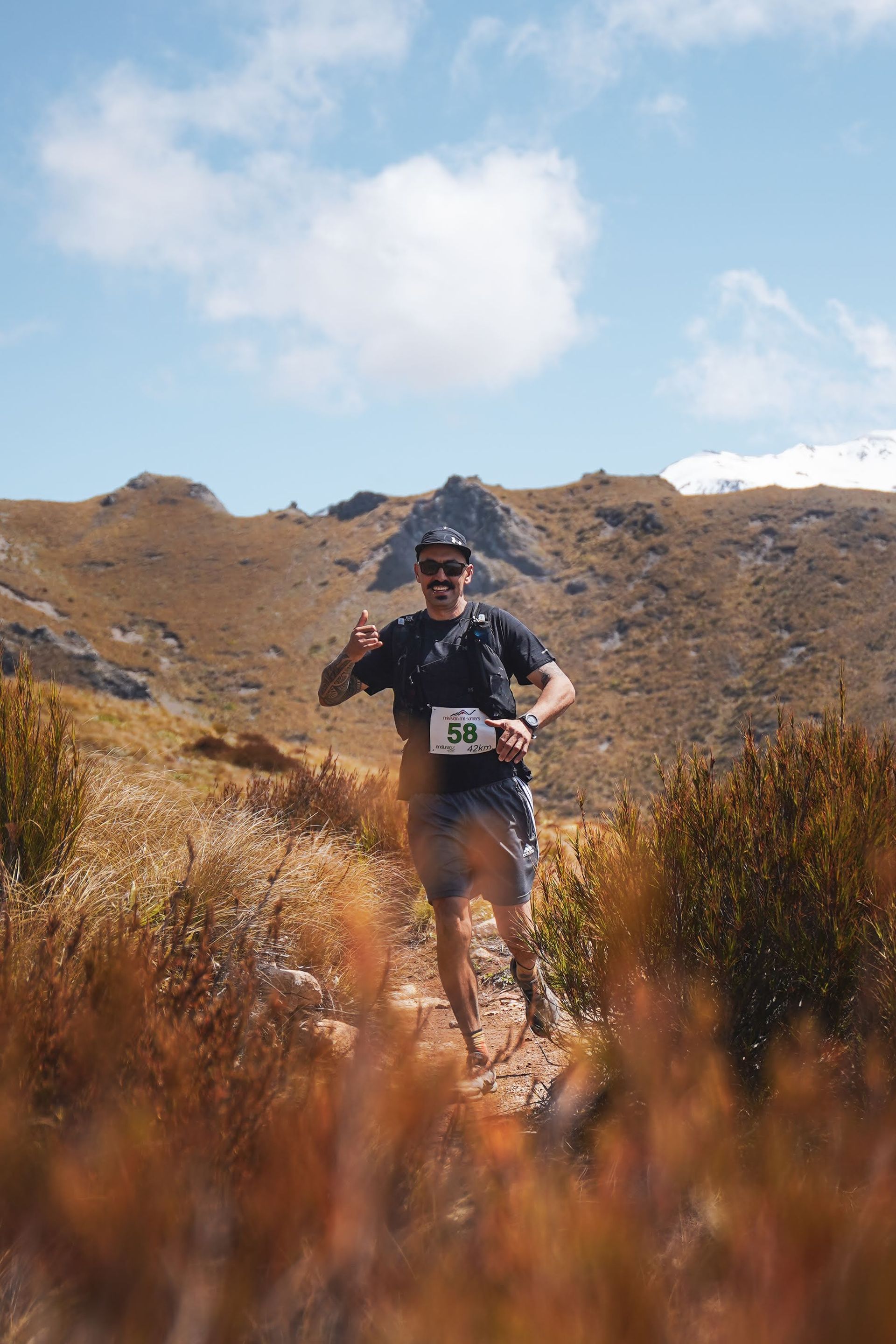 A man is running on a trail in the mountains.