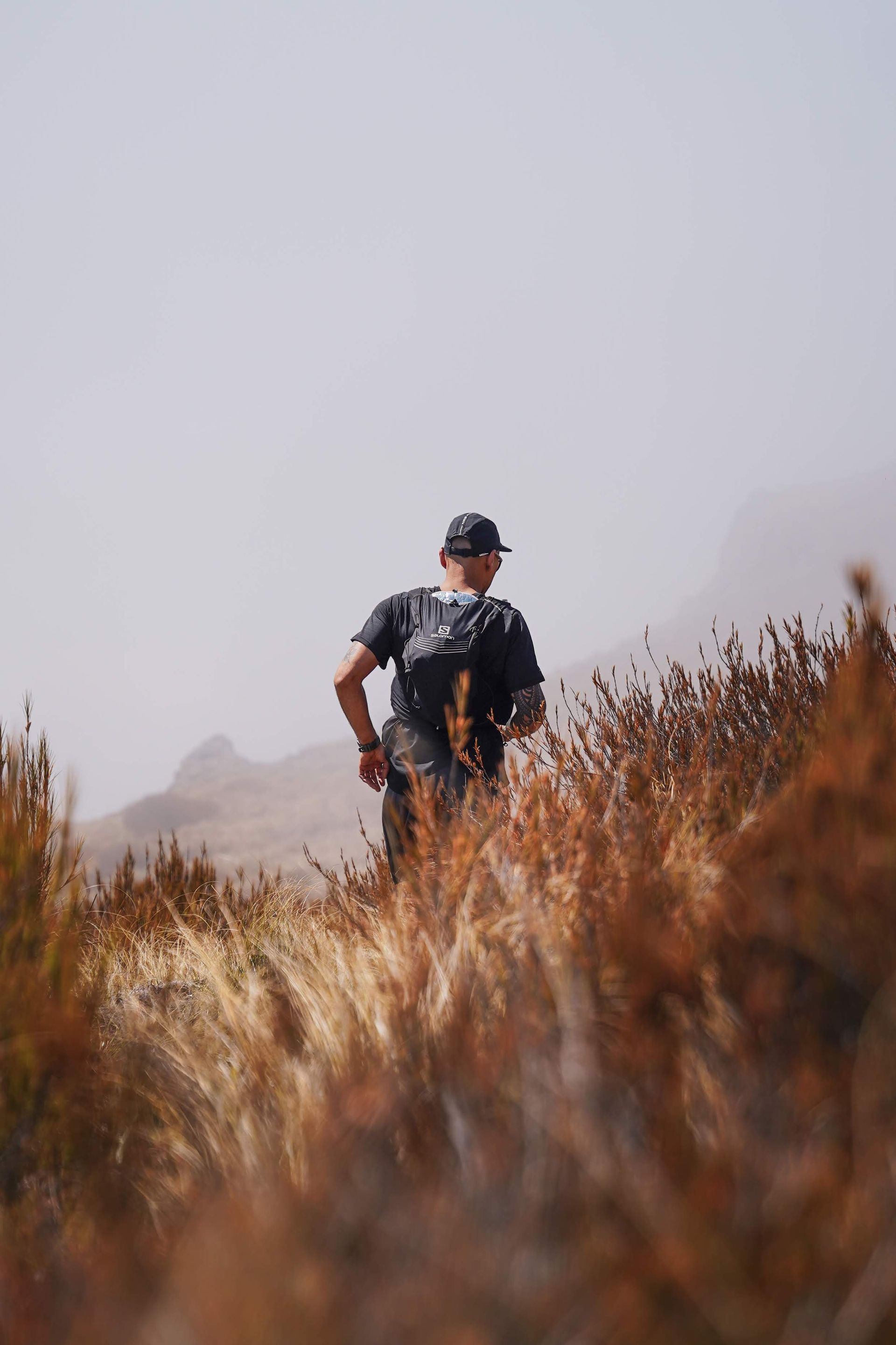 A man is walking through a field of tall grass.