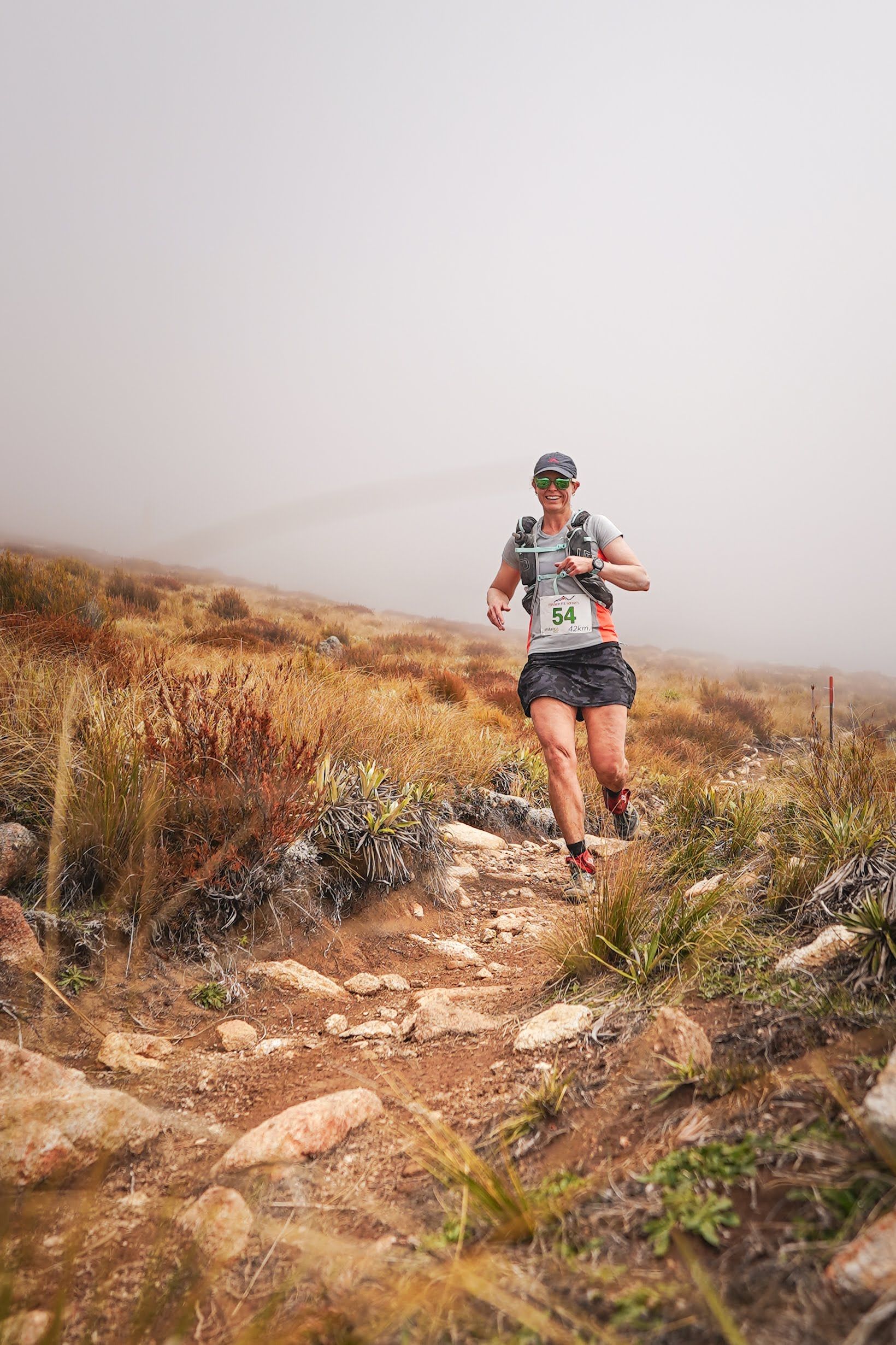 A woman is running on a trail in the fog.