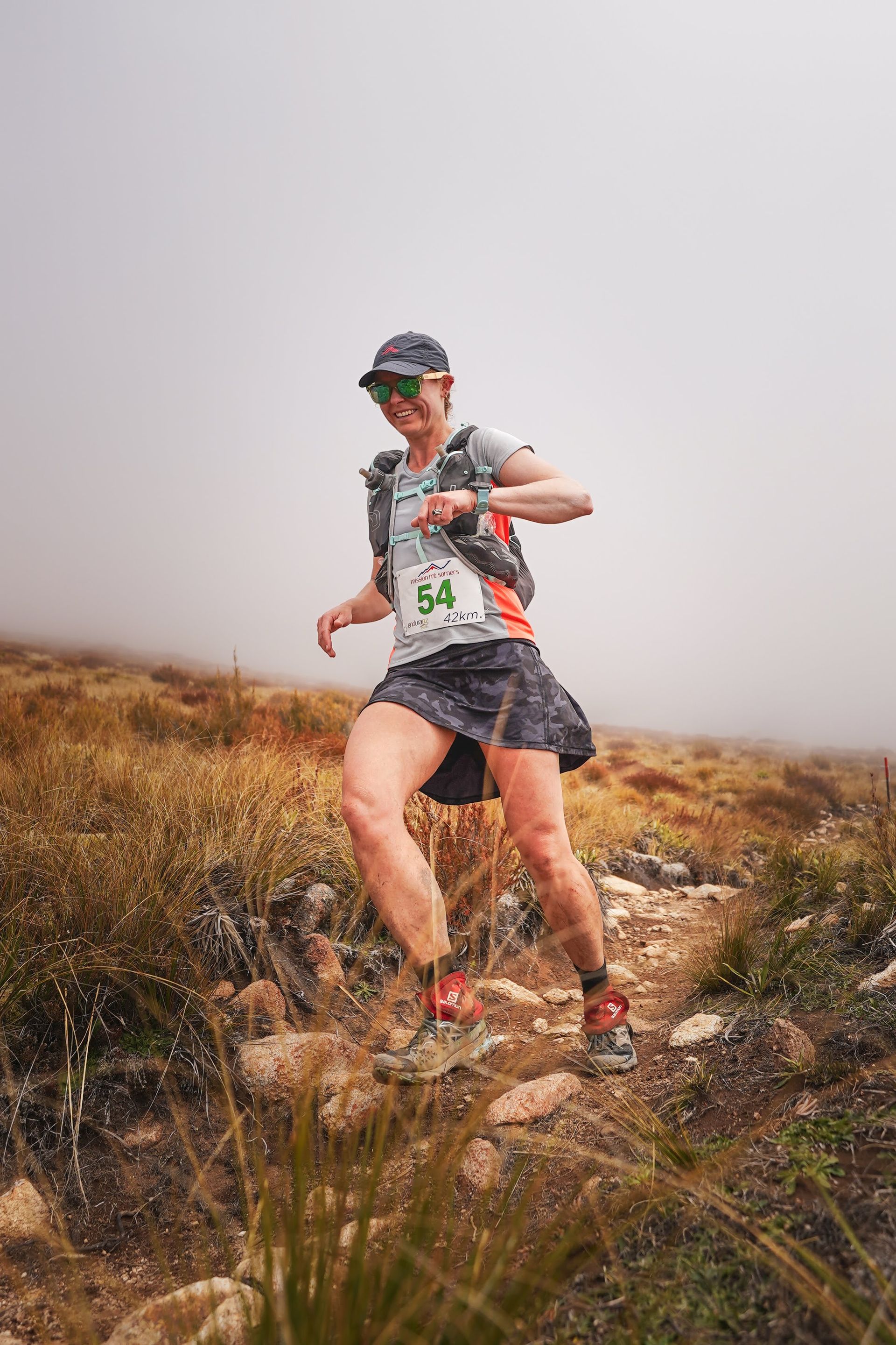 A woman is running on a trail in the mountains.