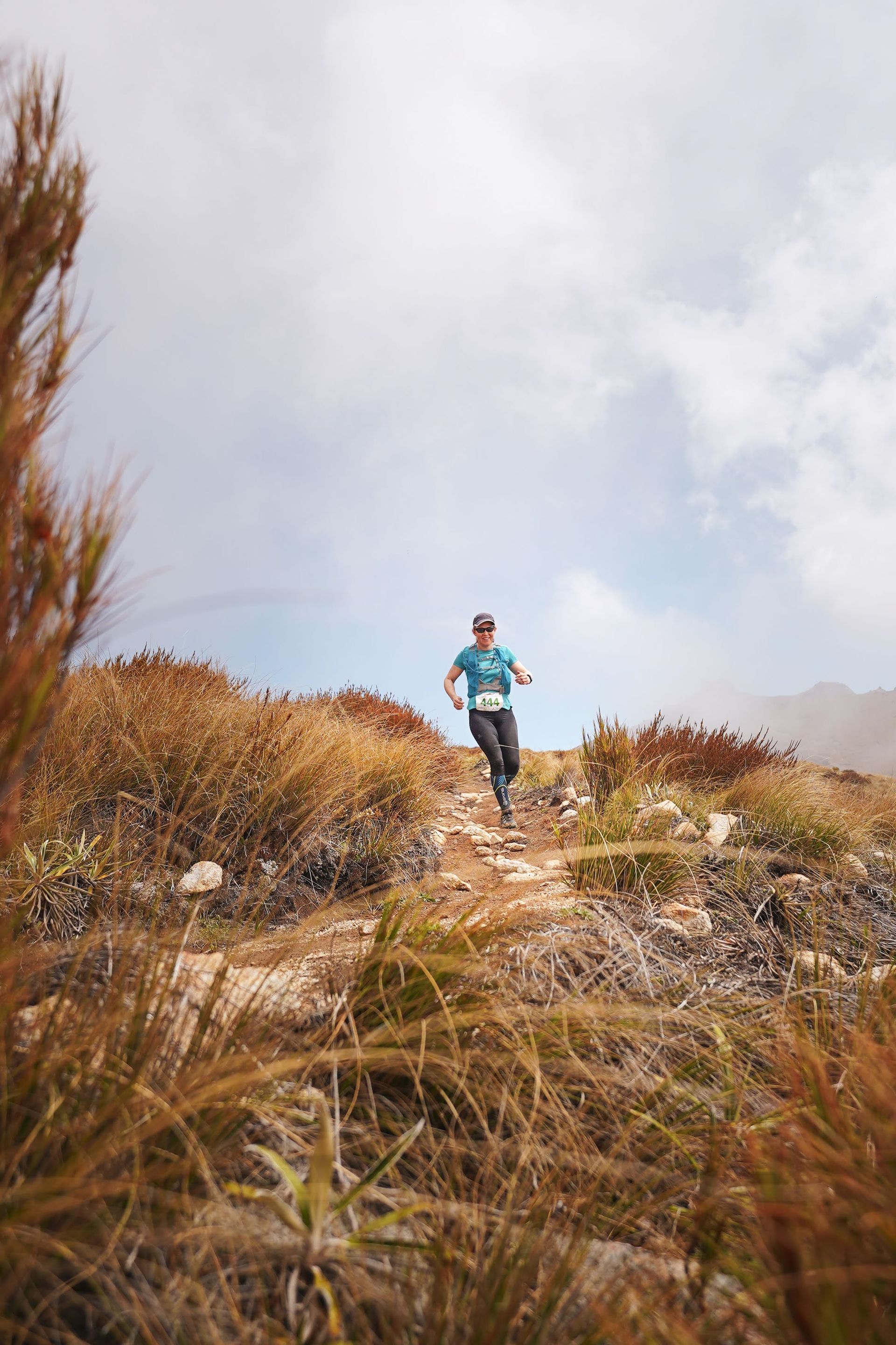 A man is running on a trail in the mountains.