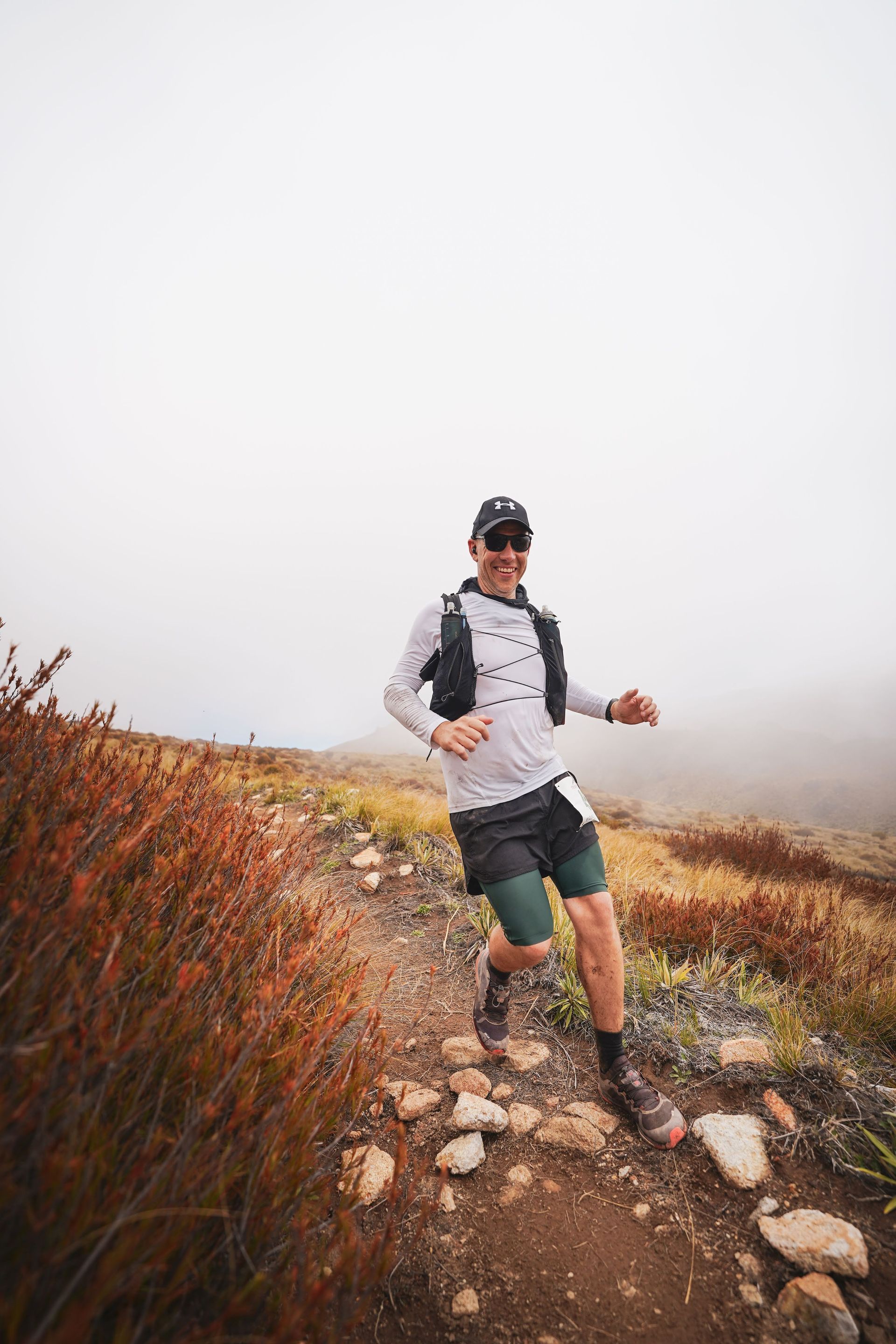 A man is running on a trail in the fog.