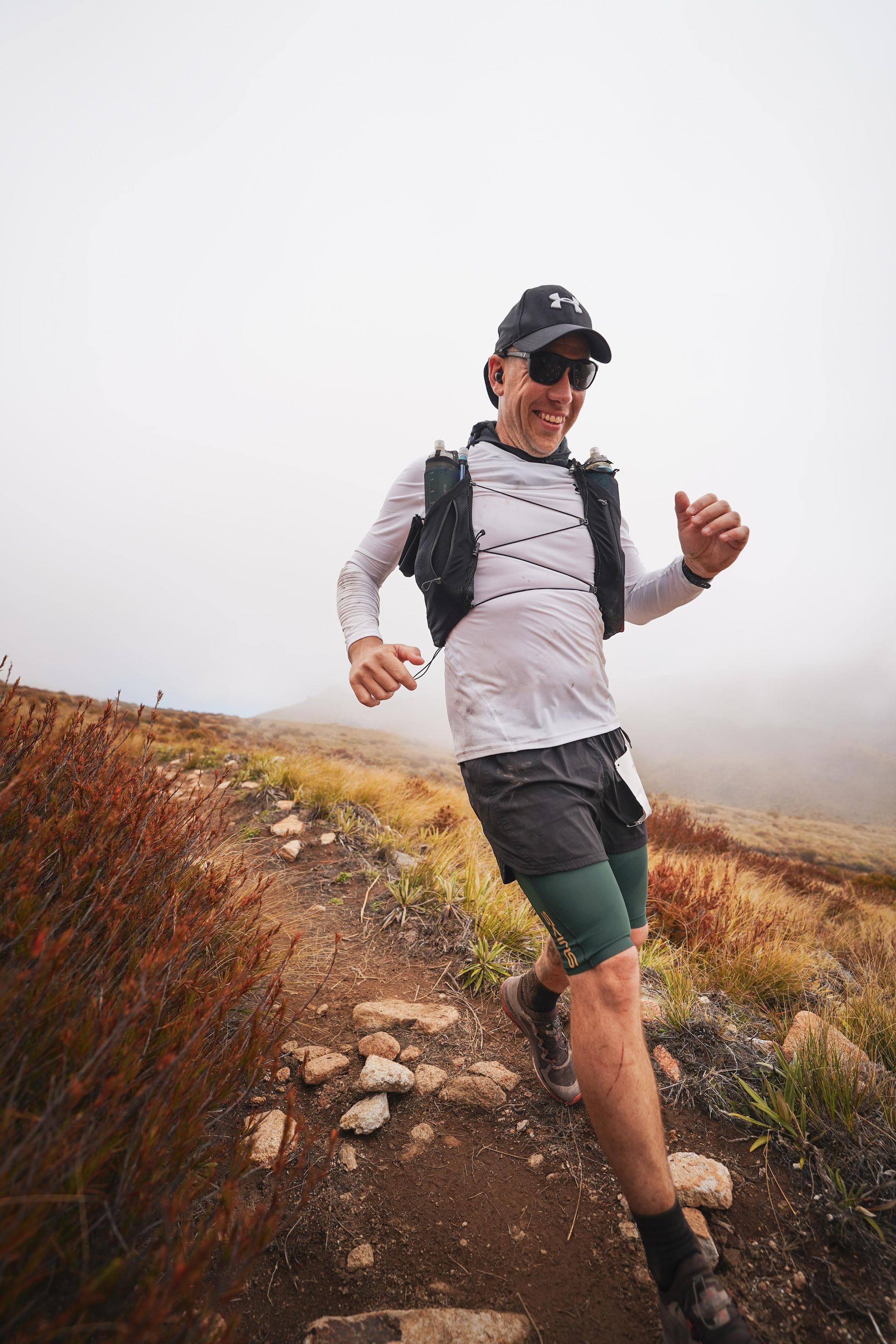 A man is running on a trail in the mountains.