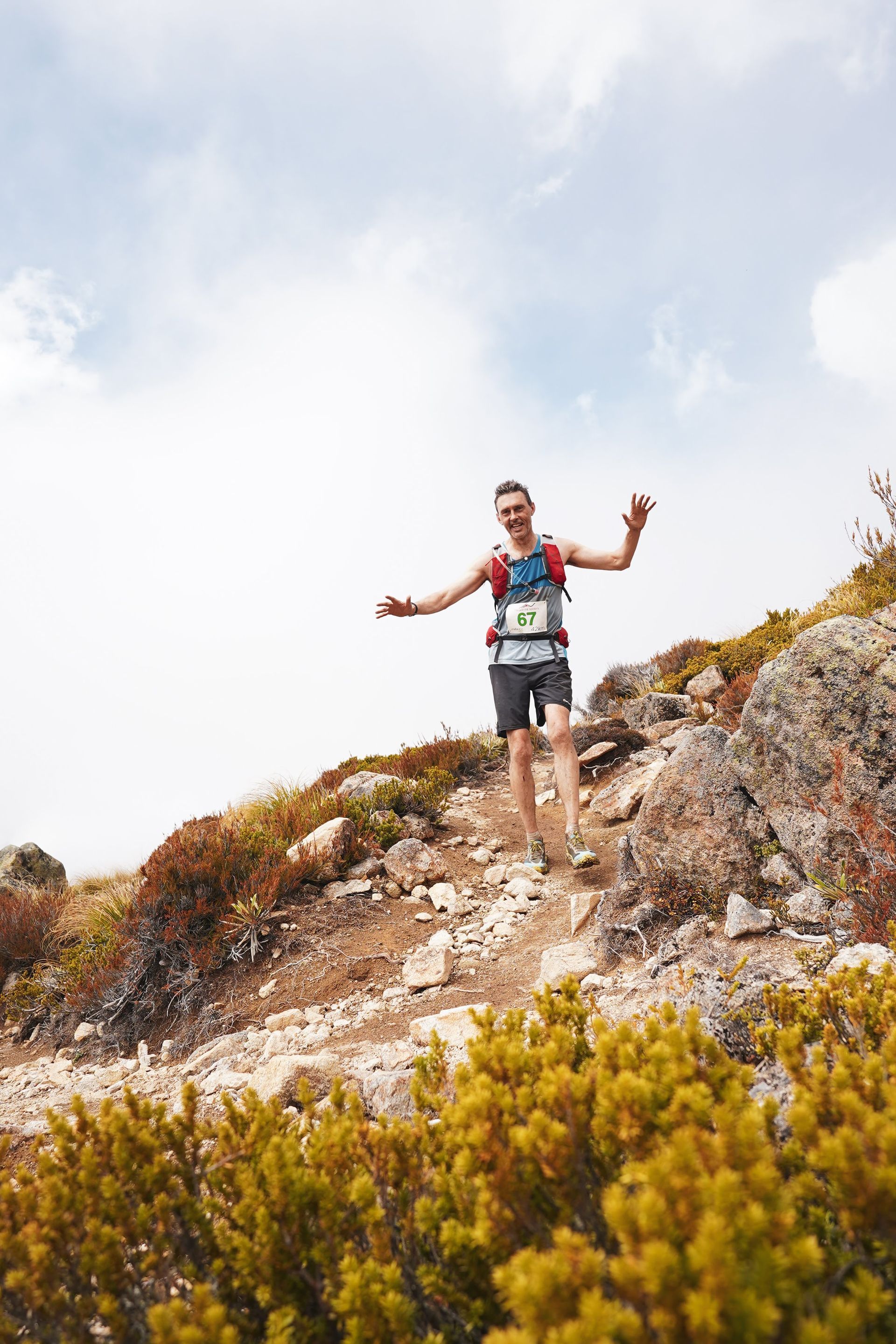 A man is running up a hill on a trail.