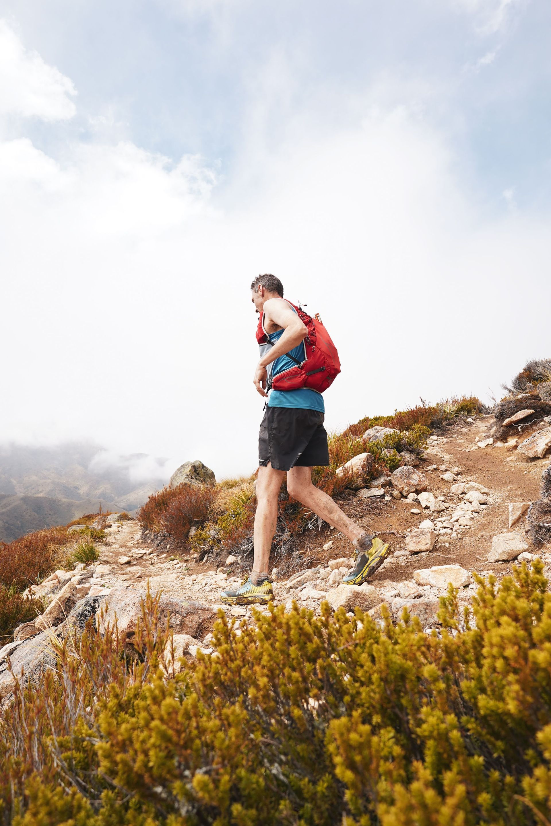 A man with a backpack is walking up a hill.