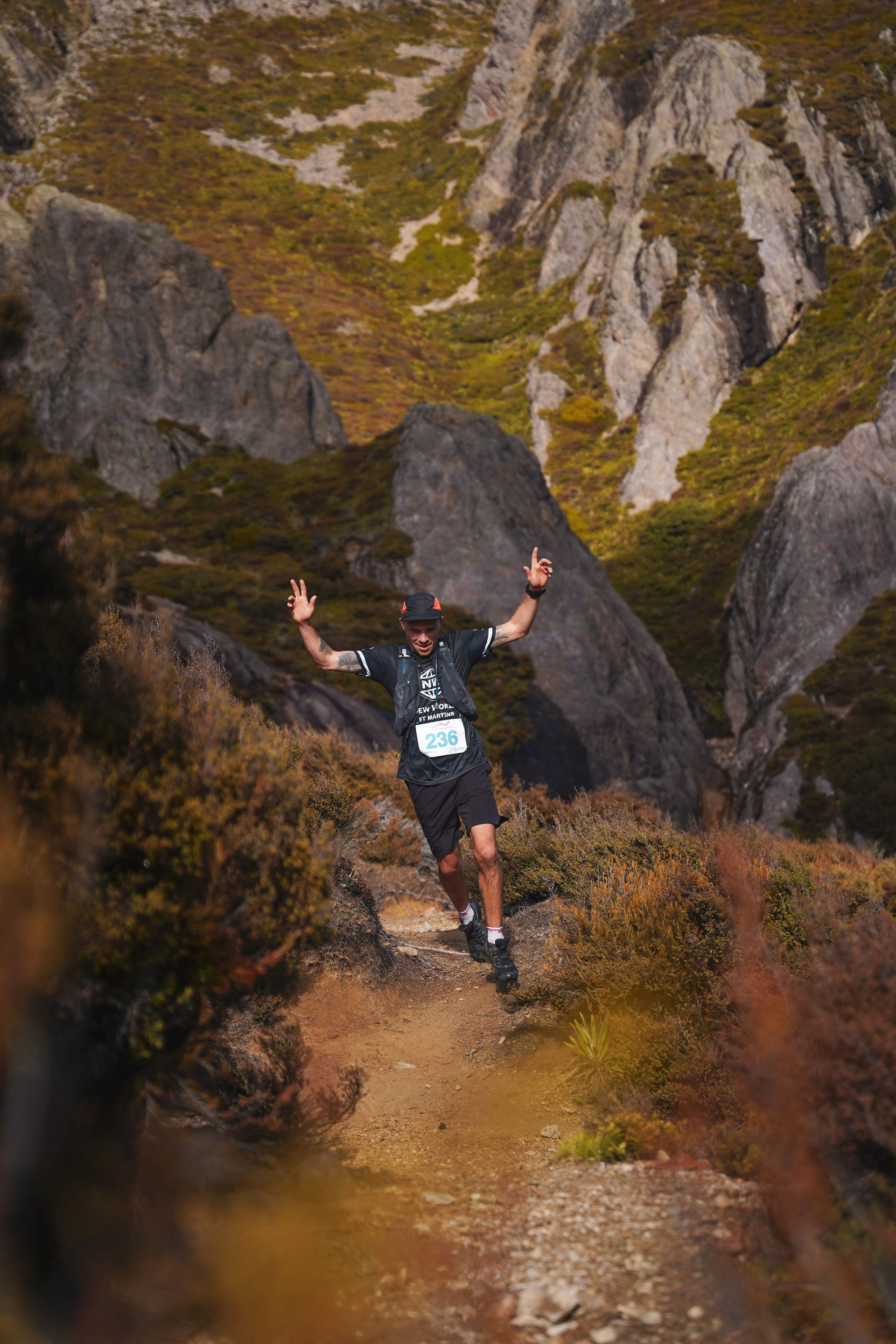 A man is running on a trail in the mountains.