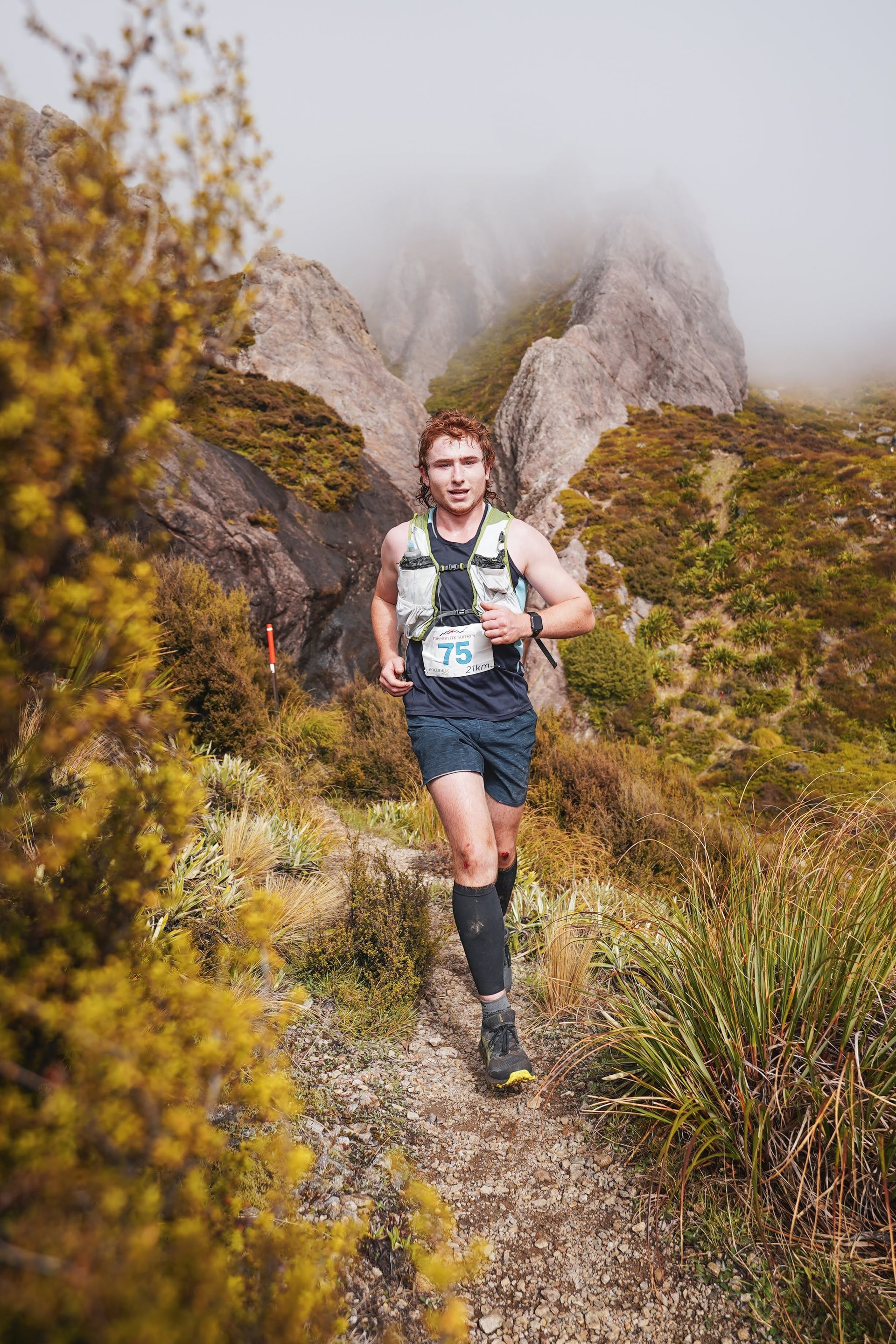 A man is running on a trail in the mountains.